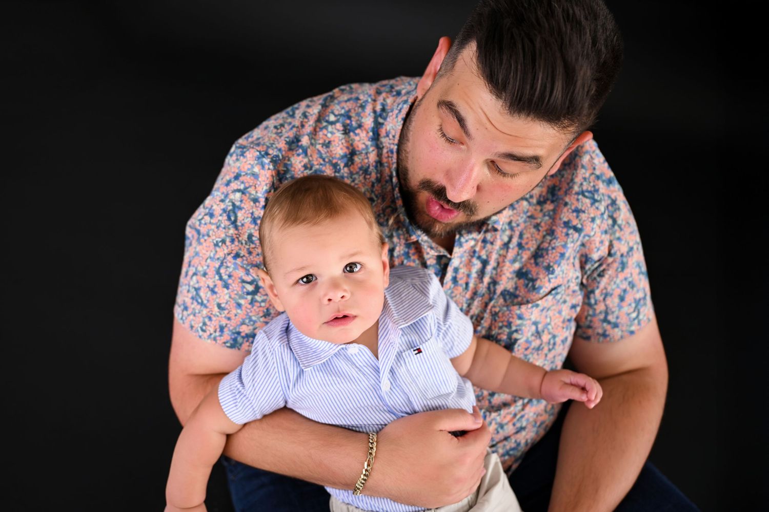 Young baby looks up at camera while Daddy holds him lovingly