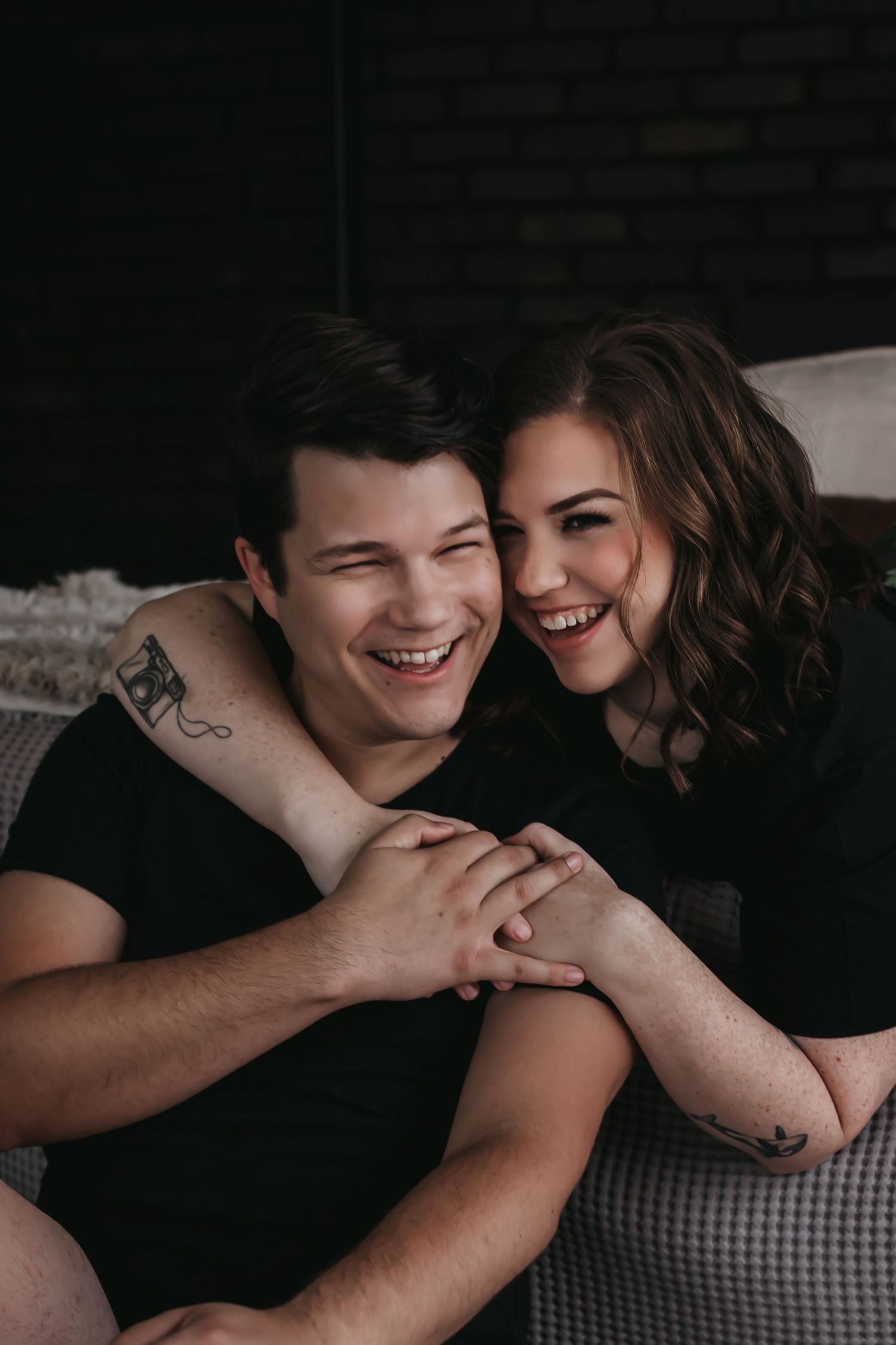Couple snuggling in pajamas in a moody photography studio