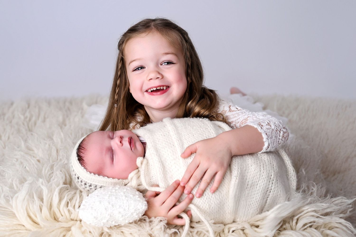 3 year old sister holds baby newborn brother