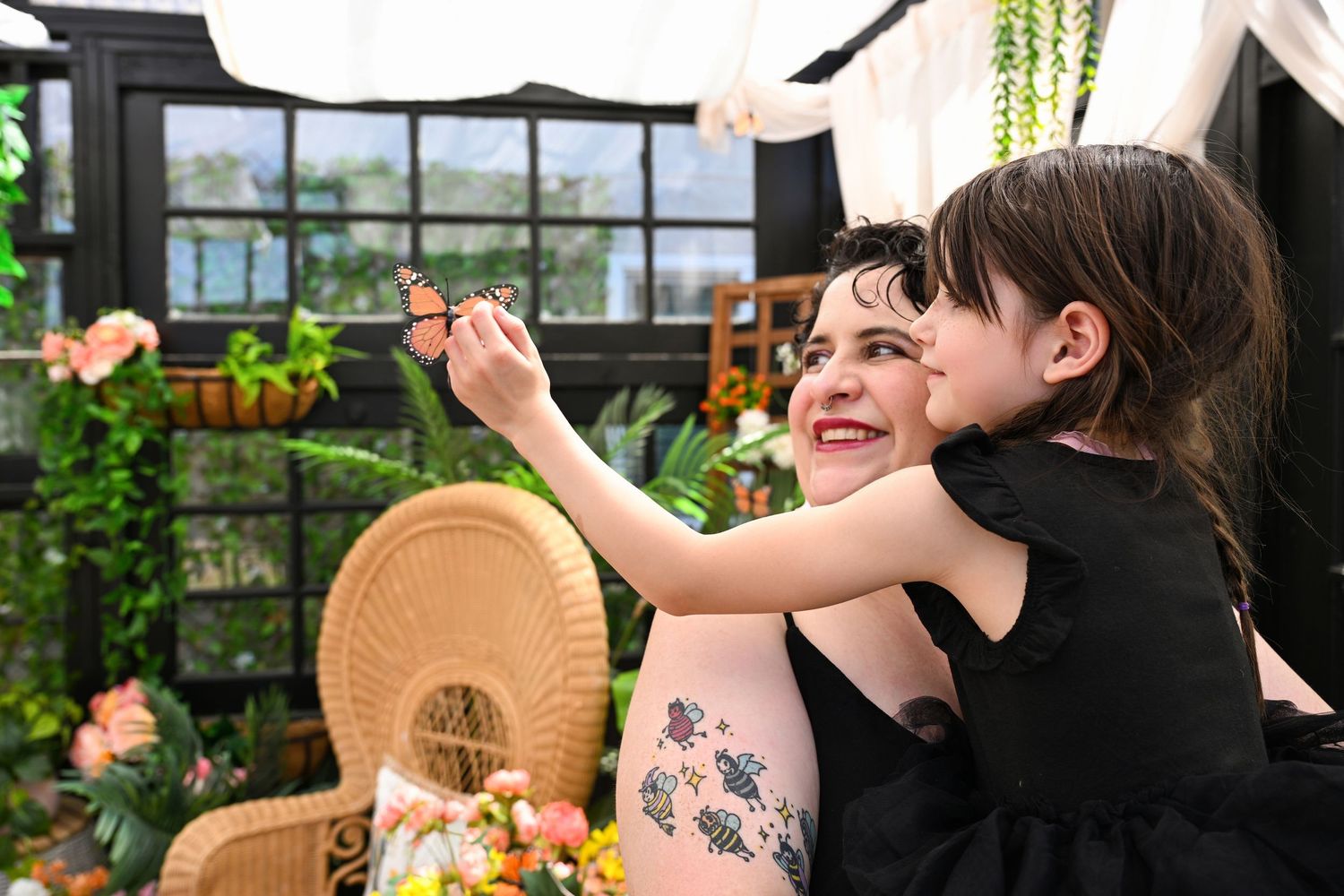 Spring time portrait of Mother and daughter looking at a monarch butterfly in Chandler Arizona Greenhouse.