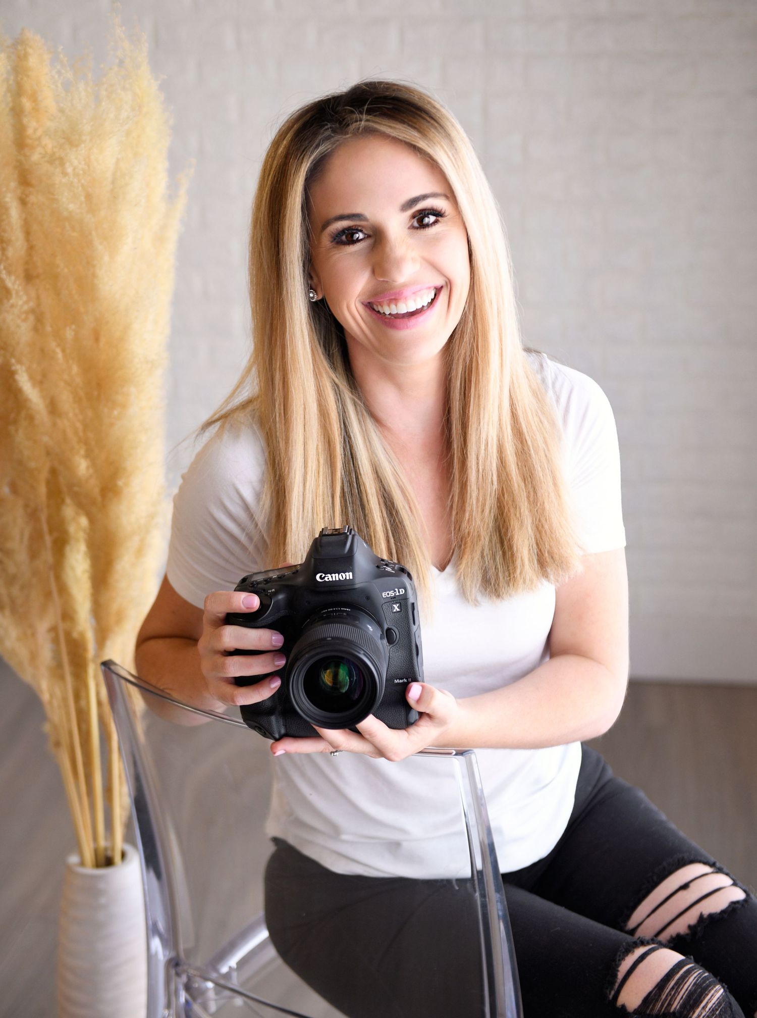 Close-up professional headshot of a woman smiling confidently in a minimalist studio photographer headshot