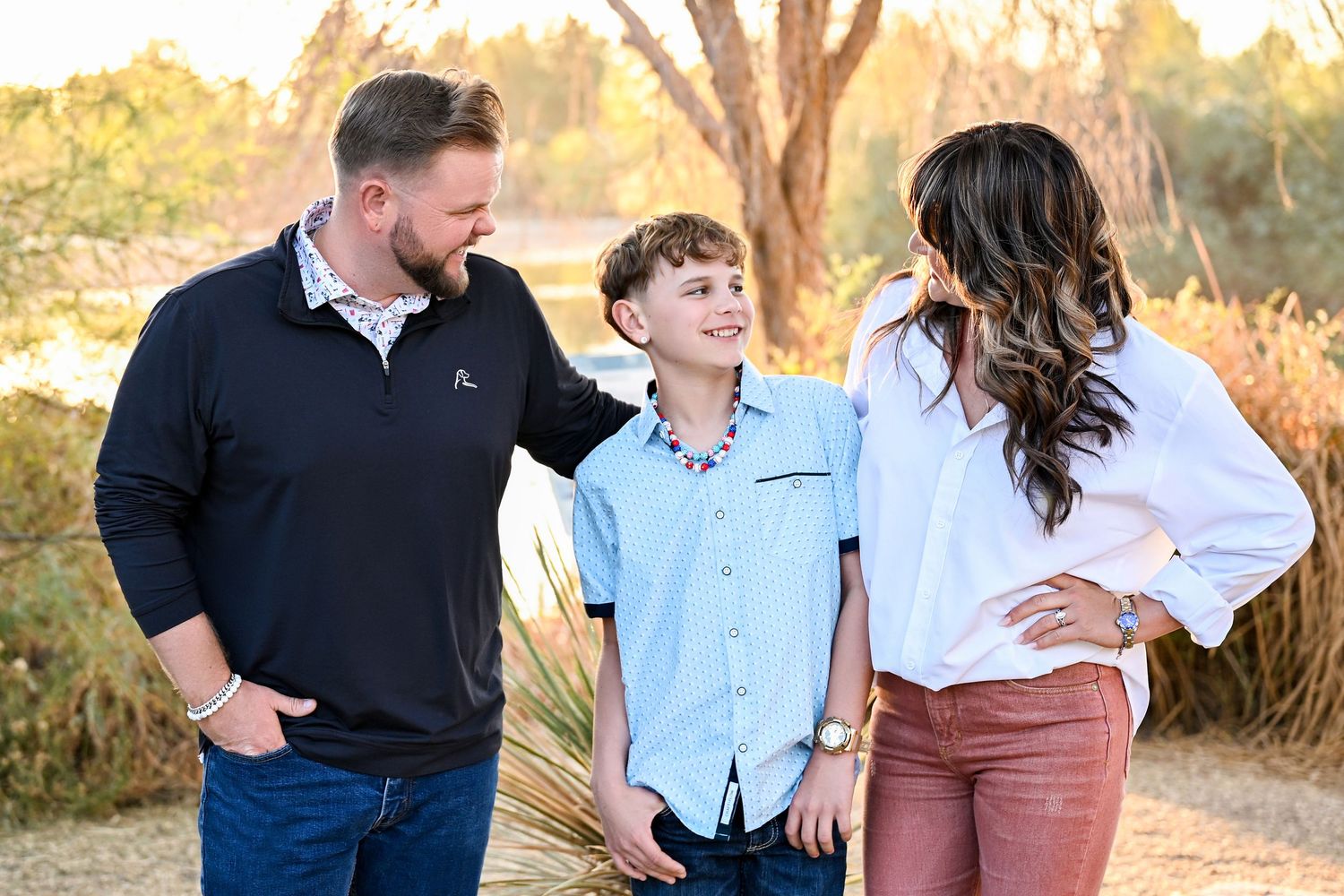 A small family photo of parents smiling at their teenage son in Gilbert Riparian Preserve Family Photoshoot in Arizona