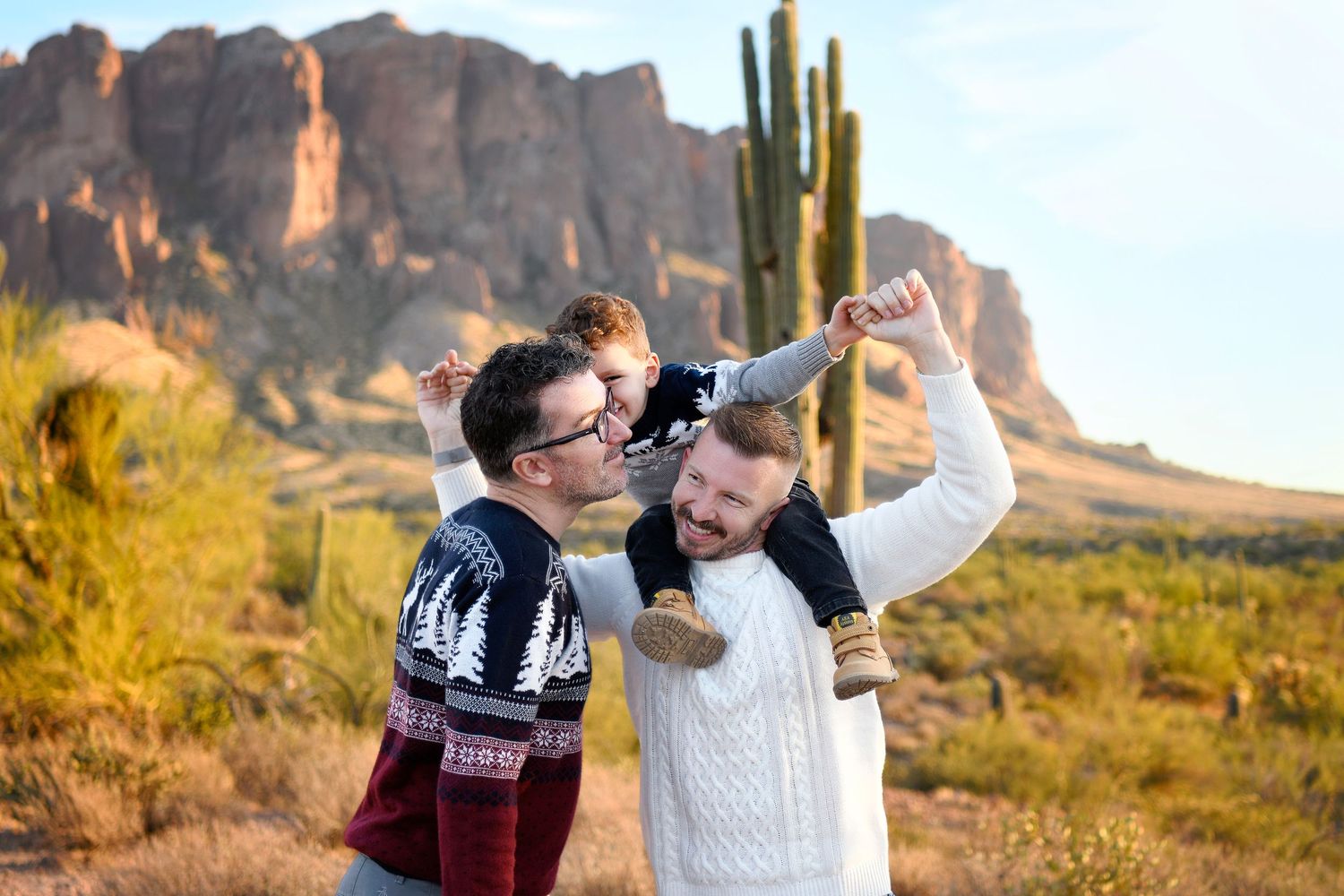 Little boy kisses daddy on the cheek while standing in a Gilbert Arizona desert family photo