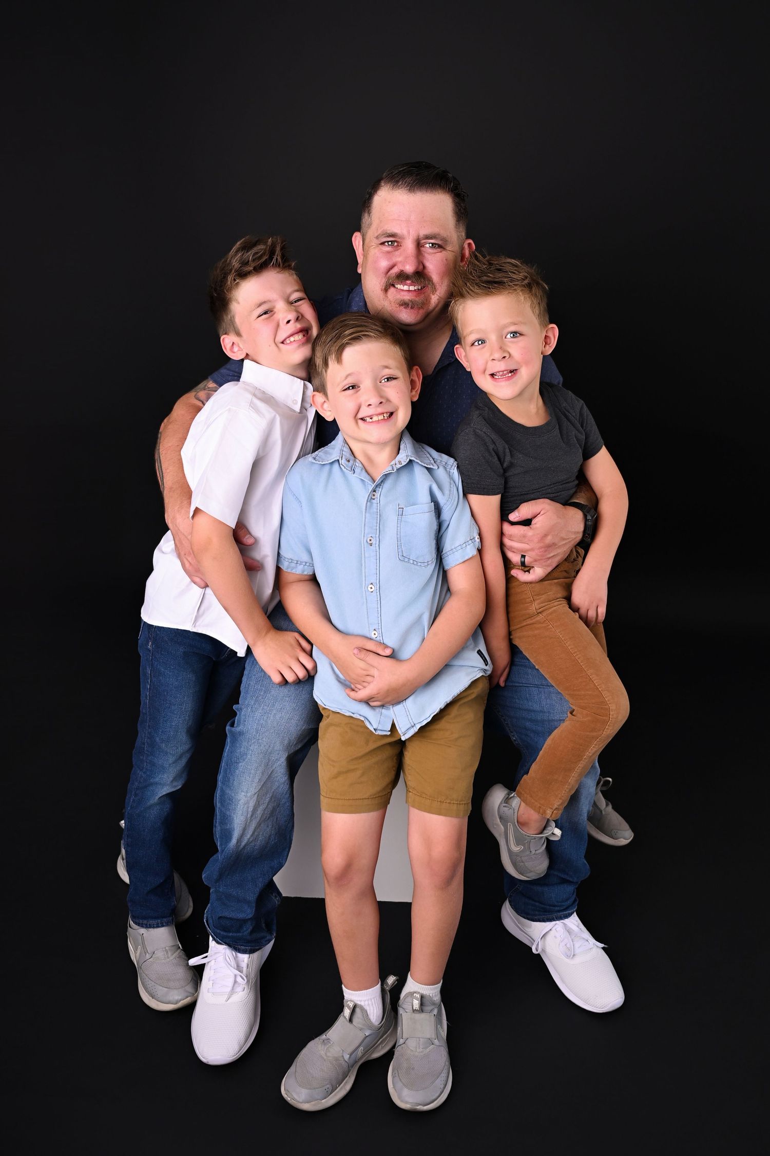 Father has his hands full holding three young laughing boys