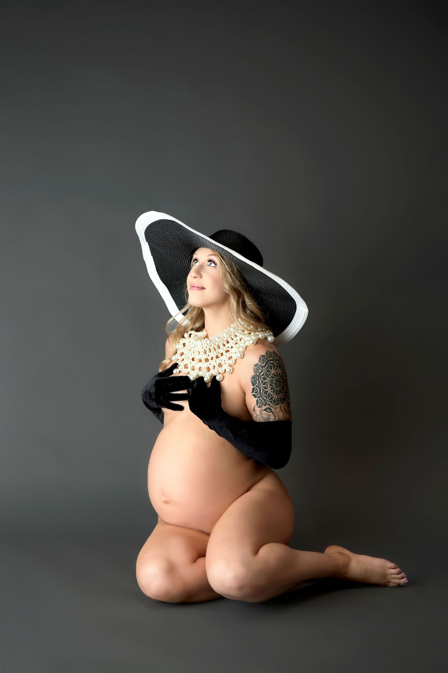 Pregnant woman sits in stunning elegant boudoir image styled in a posh way