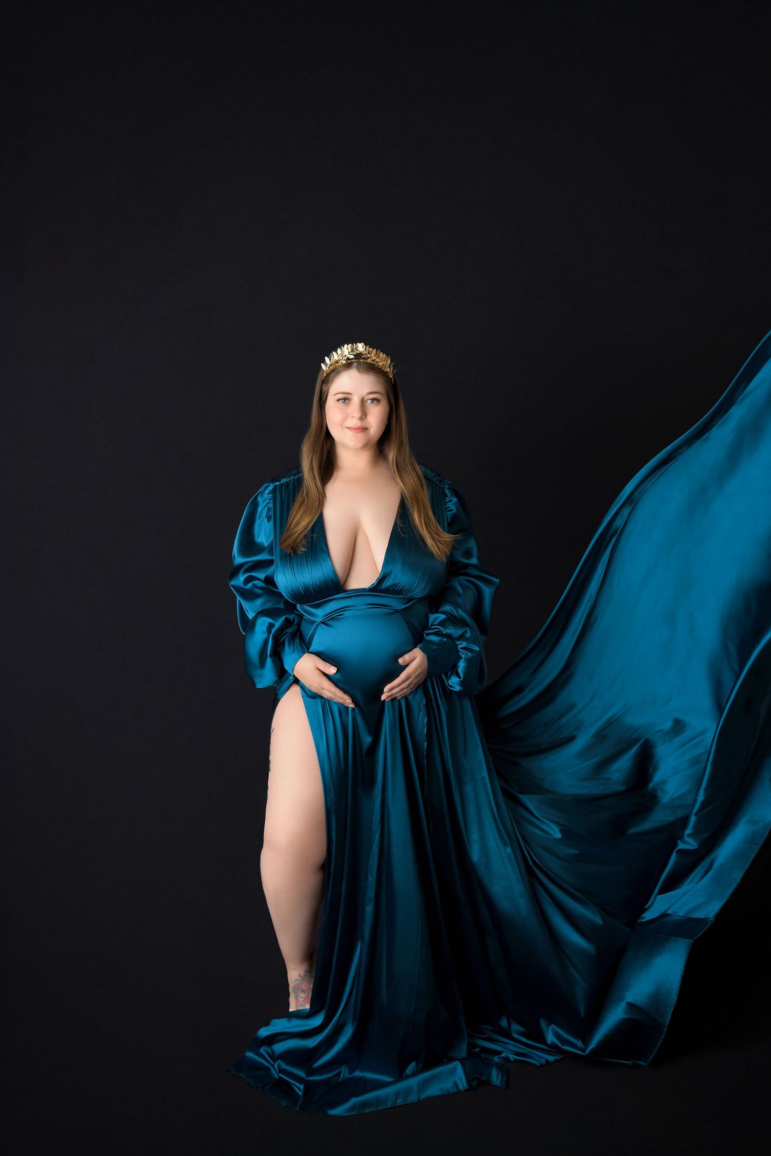Artistic maternity image emphasizing natural curves with a focus on the texture of fabrics.