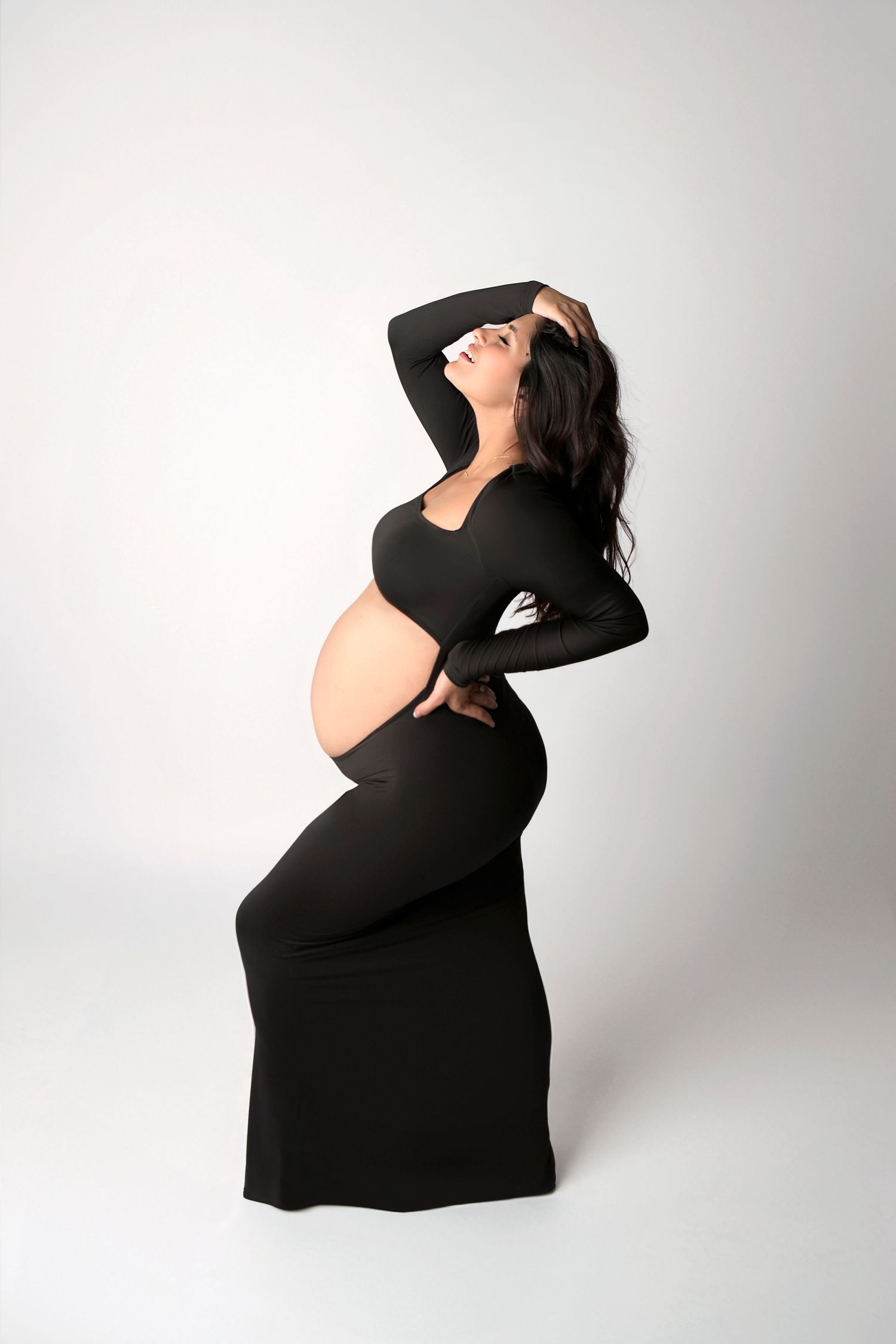 Minimalist studio maternity photo of a woman with hair styled in loose waves.