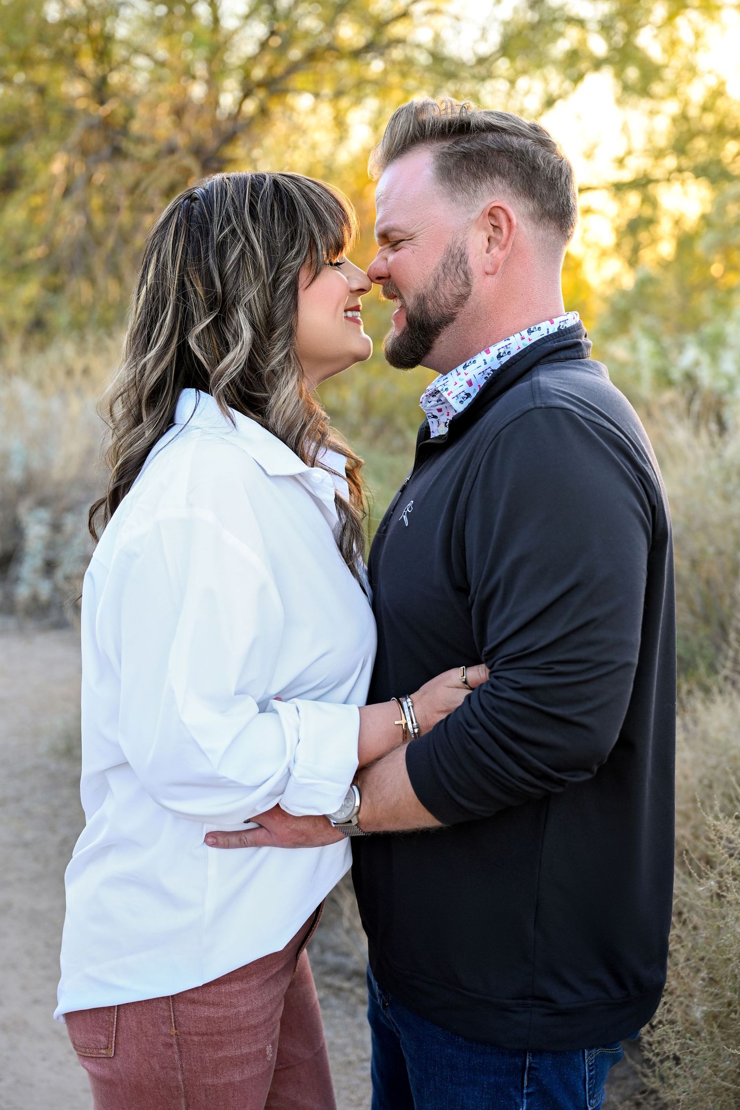 Couple dancing in a field with romantic lighting. Couple embracing with the sunset behind them.
