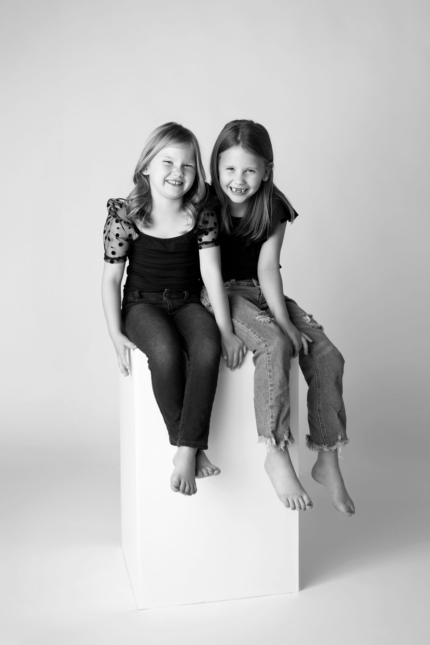 Sister's sit on a large black dressed matching for black and white portraits