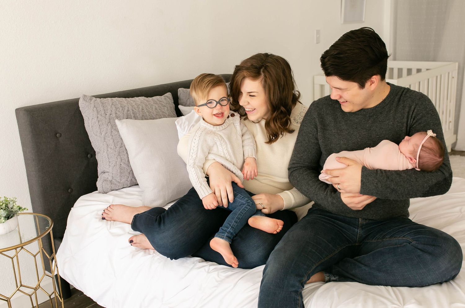 Lifestyle family photo of parents holding a newborn baby girl and toddler boy in Mesa Arizona