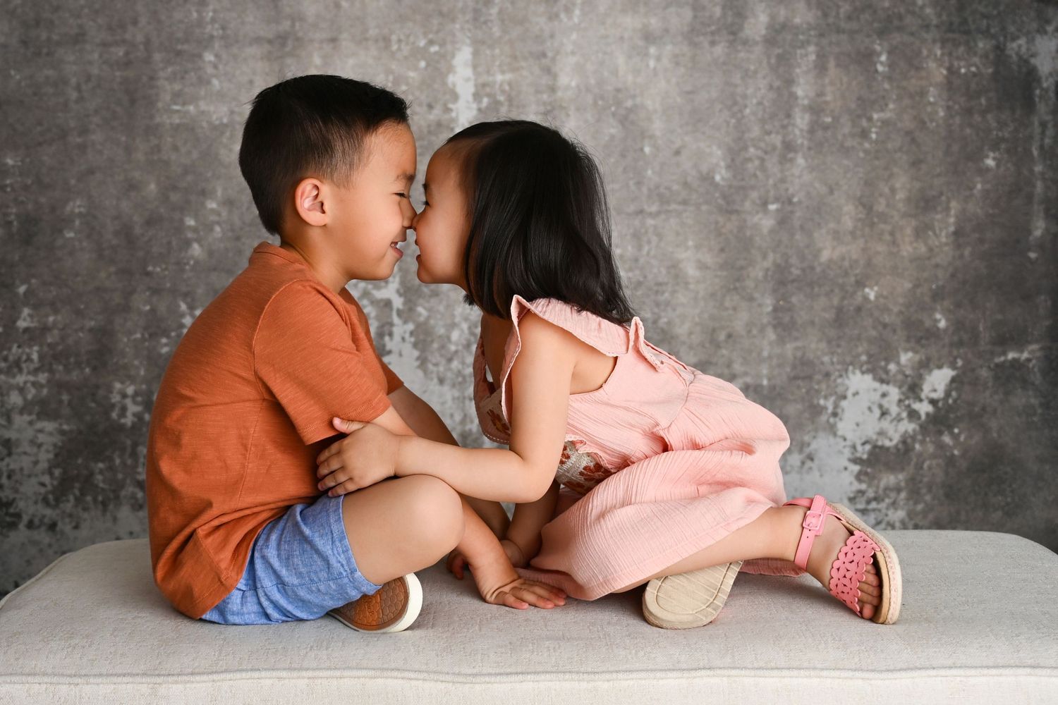 Siblings sharing a hug in a studio with neutral decor.
