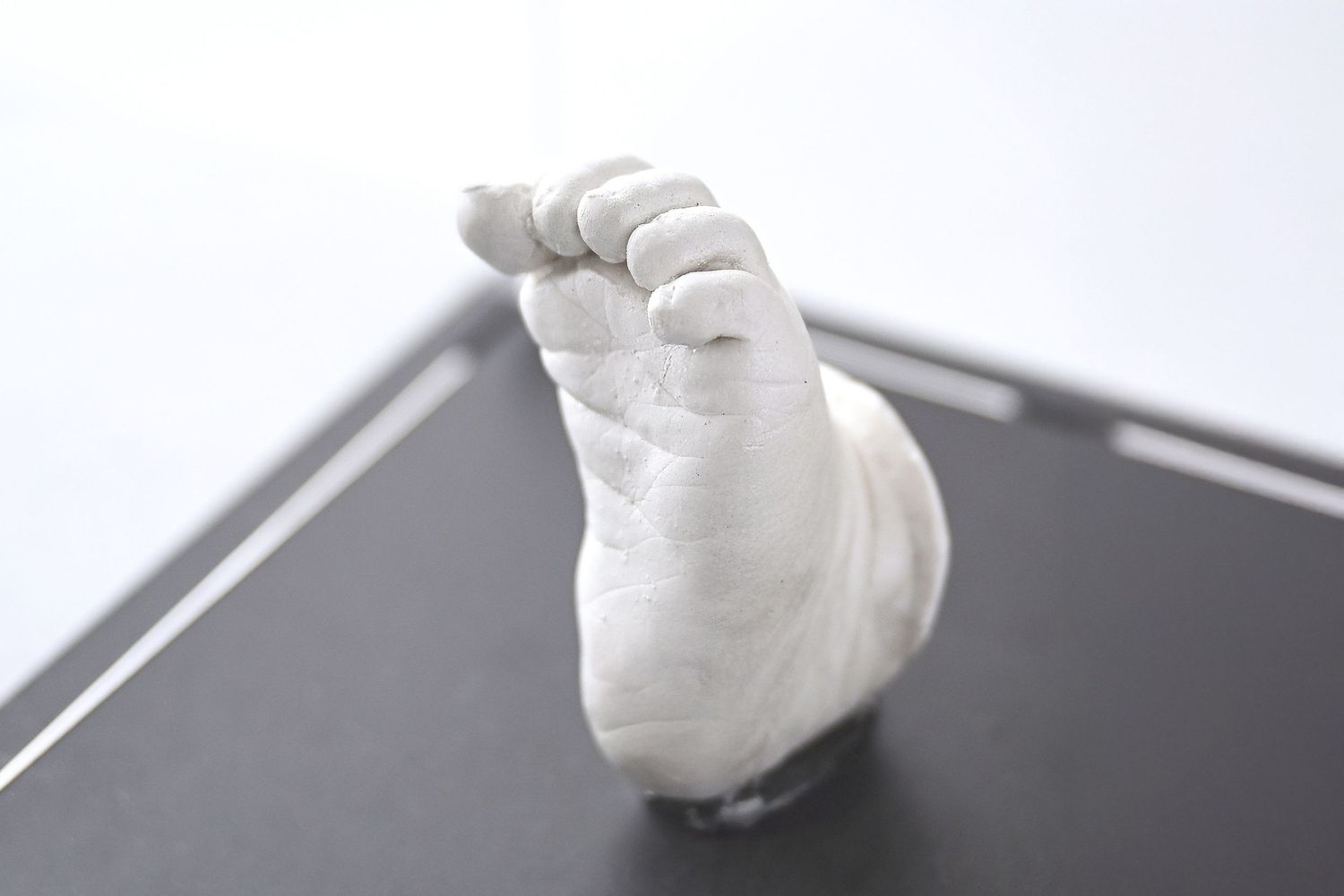 A 3D stone casting of a newborns foot showcasing the toes and little foot creases. It is inside of an acrylic case and was handmade in AZ