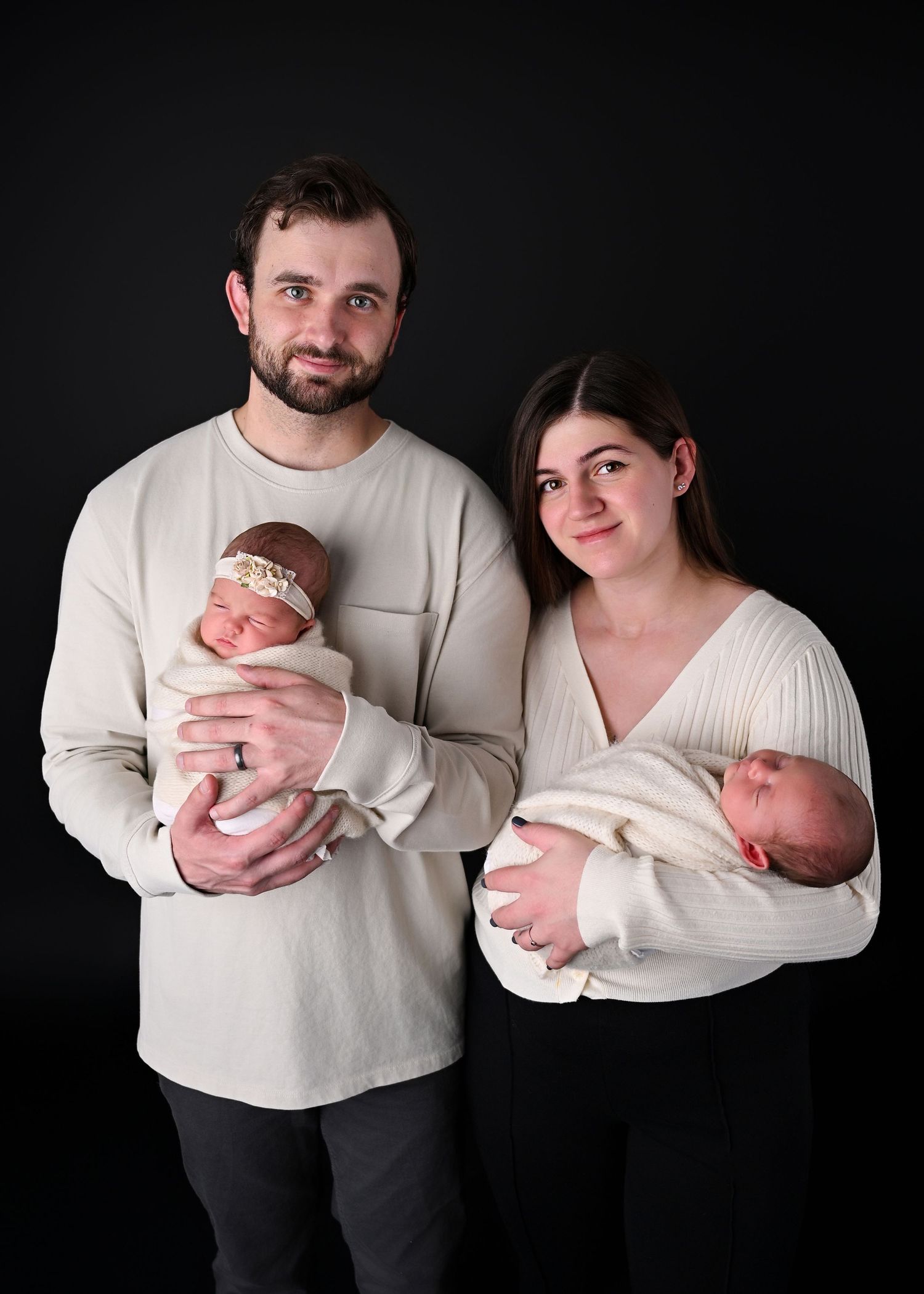 New parents holding their brand new twin baby's on  a black backdrop
