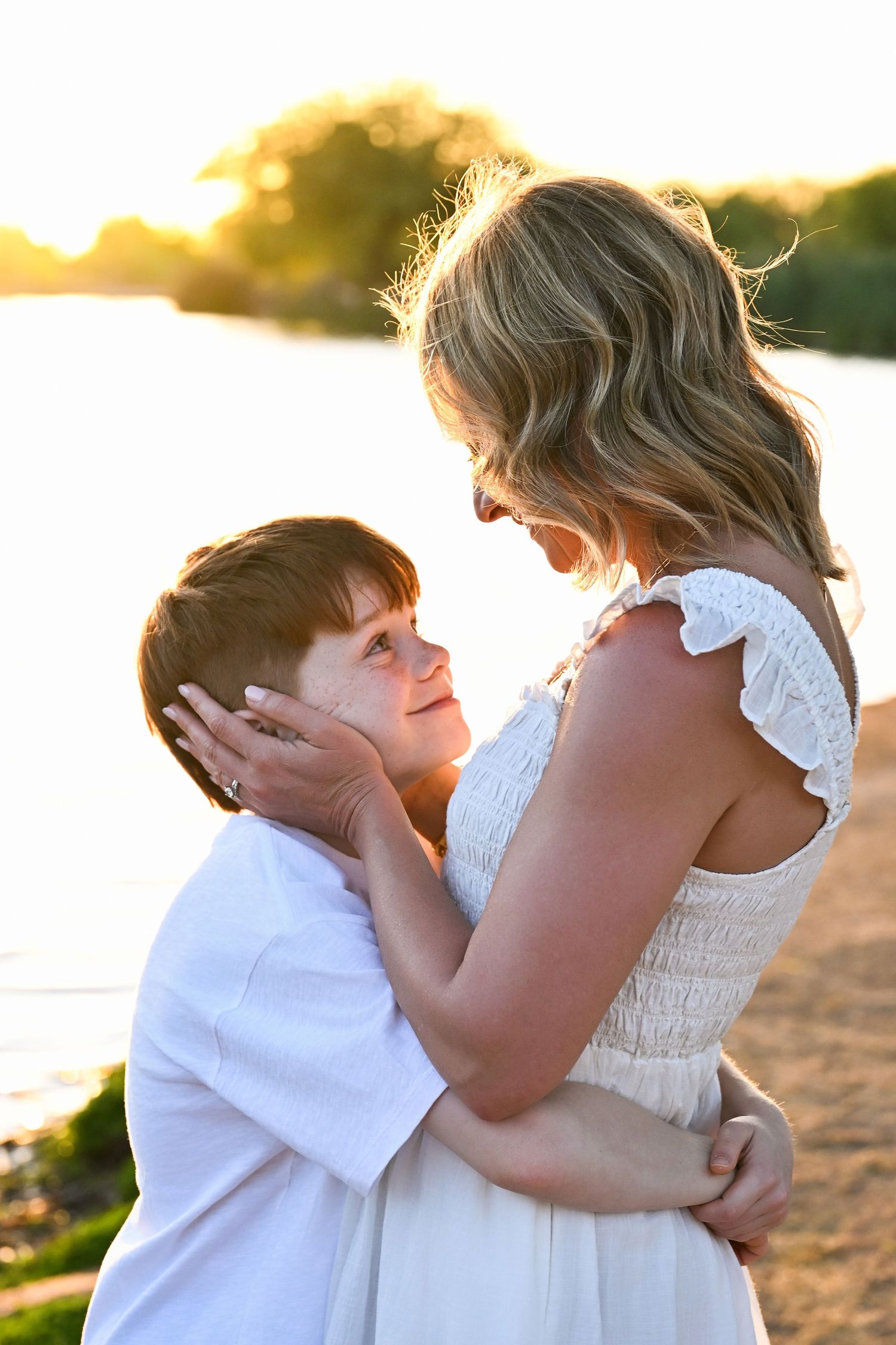 Mother holds suns face in loving embrace by Arizona lake in Chandler park