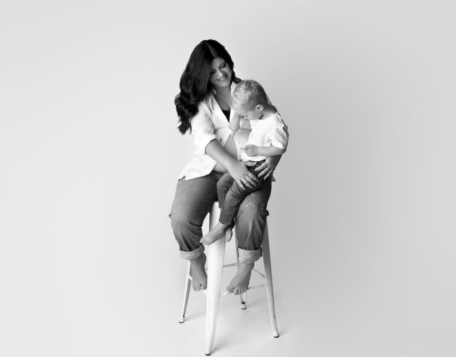 Young family with toddler touching a baby bump in photo studio