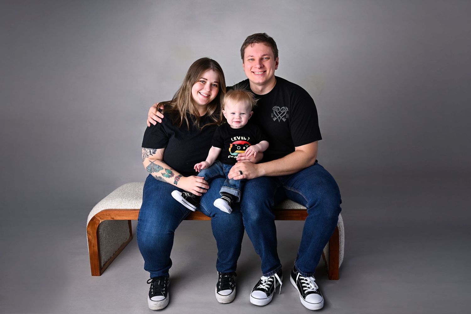 Happy parents in matching t-shirts holding their smiling toddler during a family portrait session in Phoenix, Gilbert, or Chandler AZ