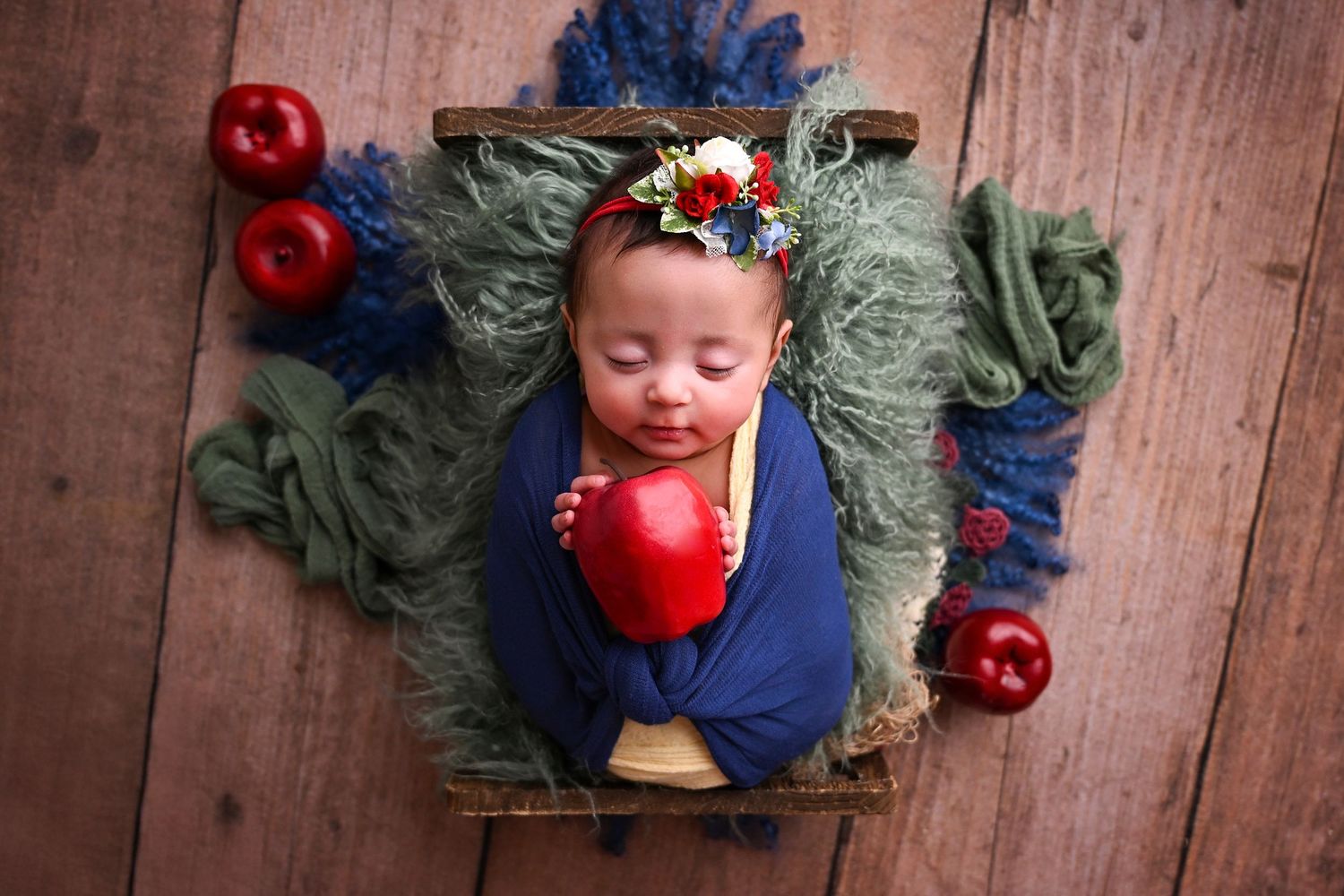 Snow White themed Newborn photoshoot of baby holding an apple