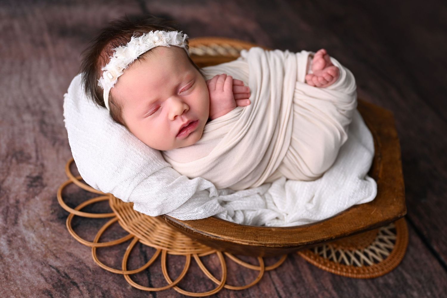 Baby sleeping peacefully on a soft, neutral blanket inside of a bowl