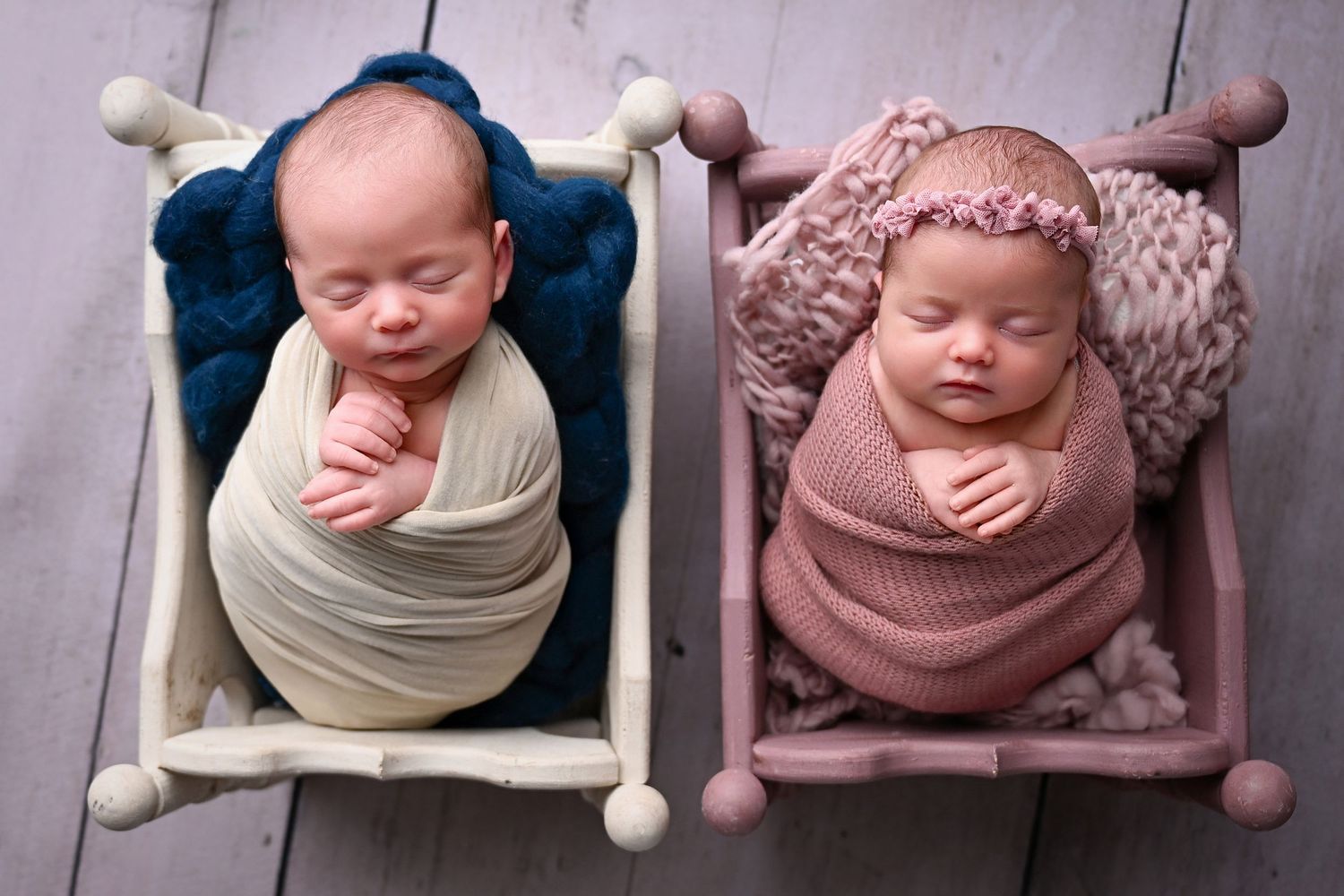 Newborn Twins laying in two miniature cribs side by side