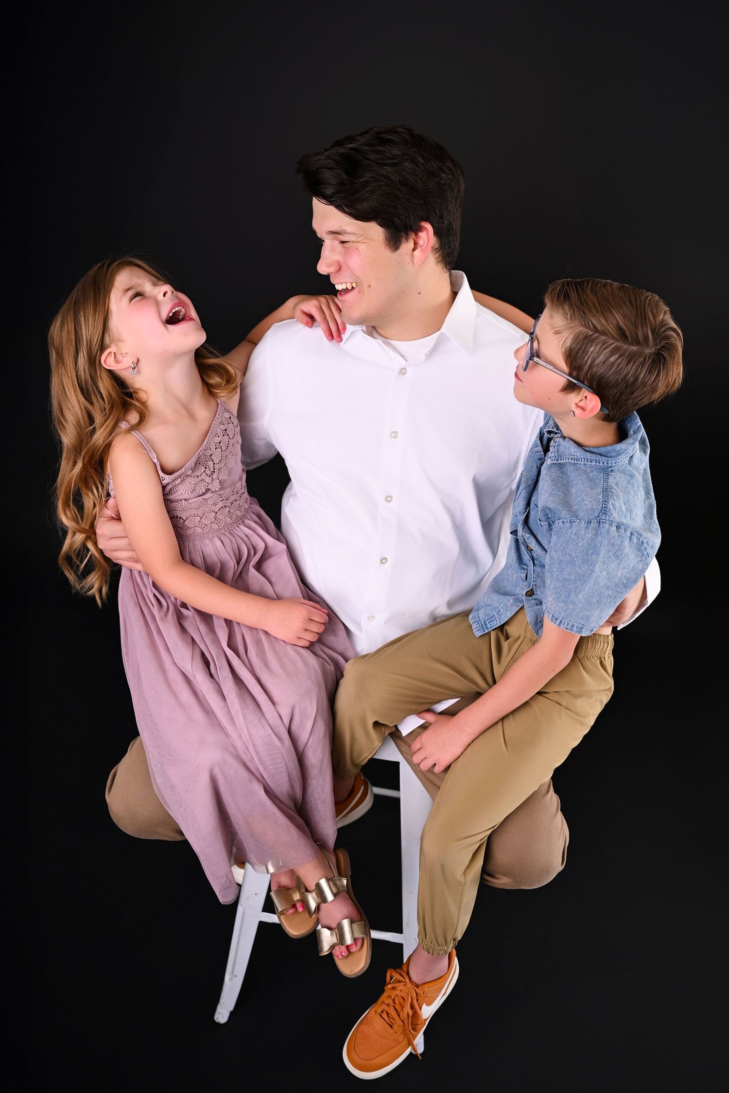 Father in photo studio holding two children laughing at each other for Fathers Day