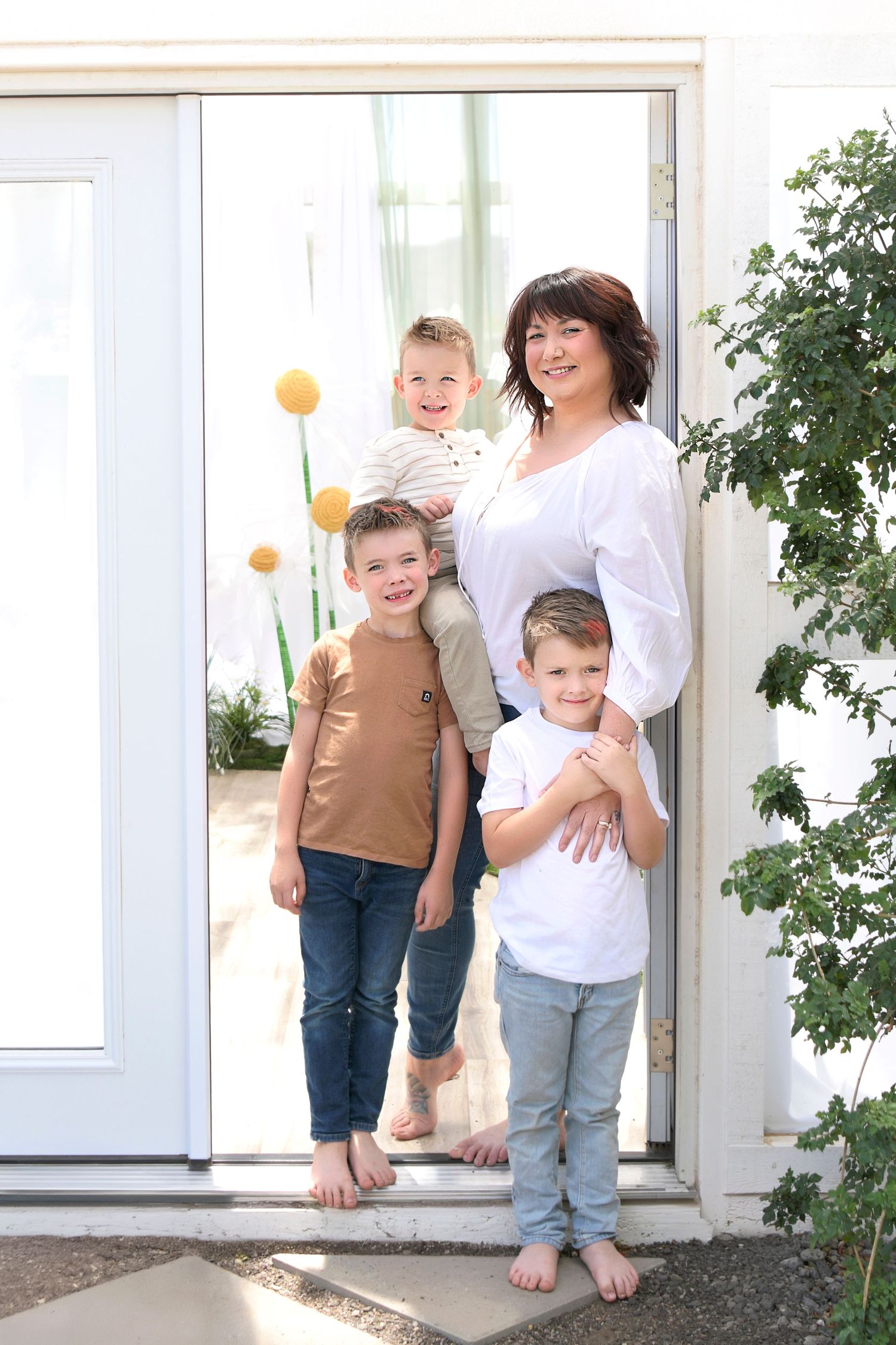 Mothers stands in the doorway of a white house holding her children close