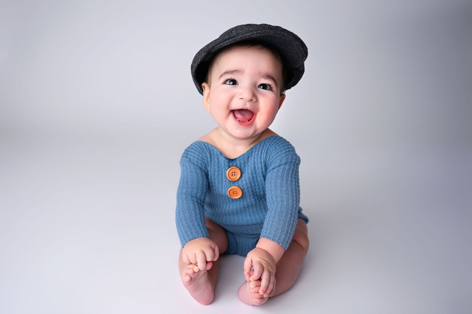 Sitter Session portrait of baby in a hat wearing clothes from the client closet in Phoenix