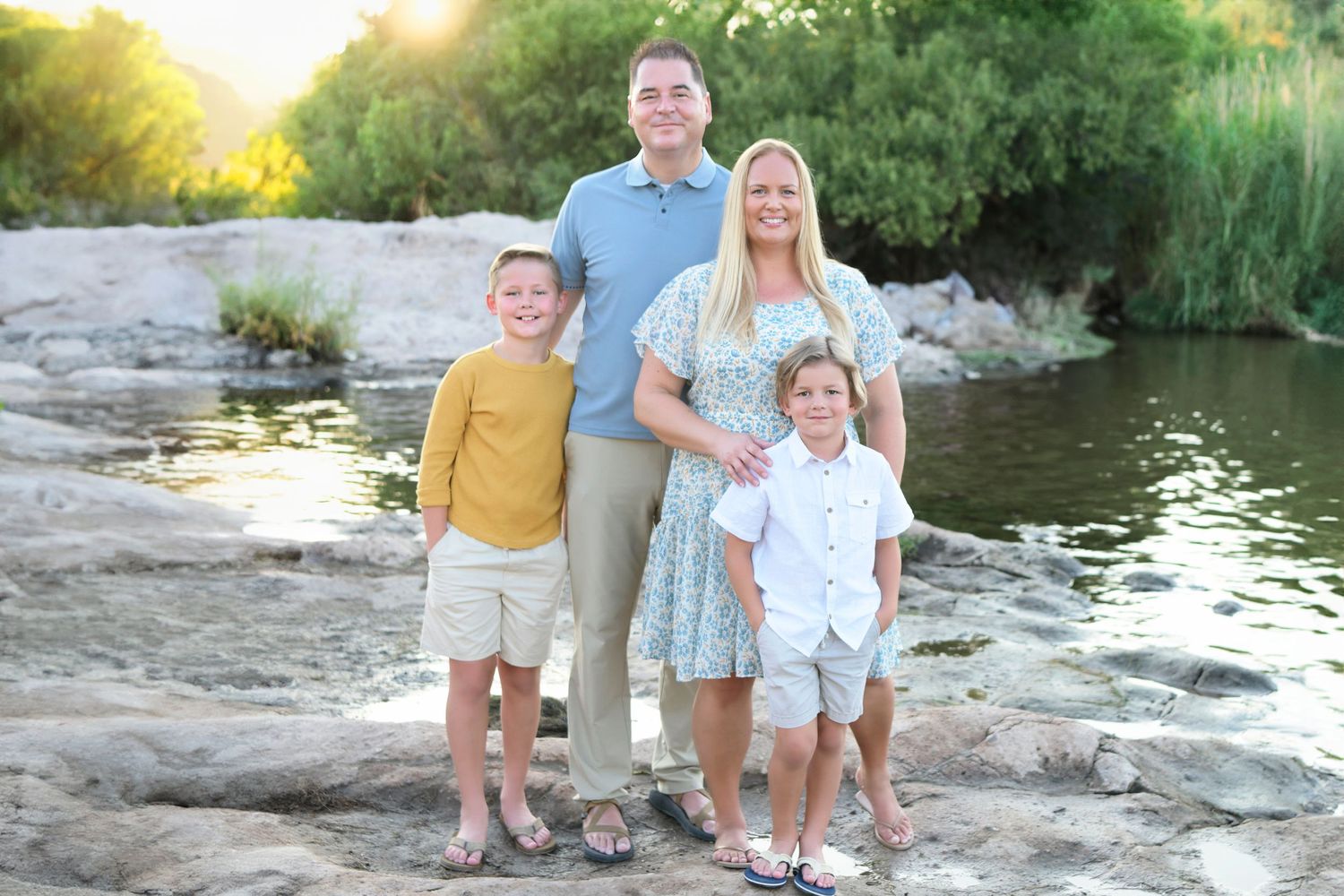 Family standing on rocks with a lake view in the background.