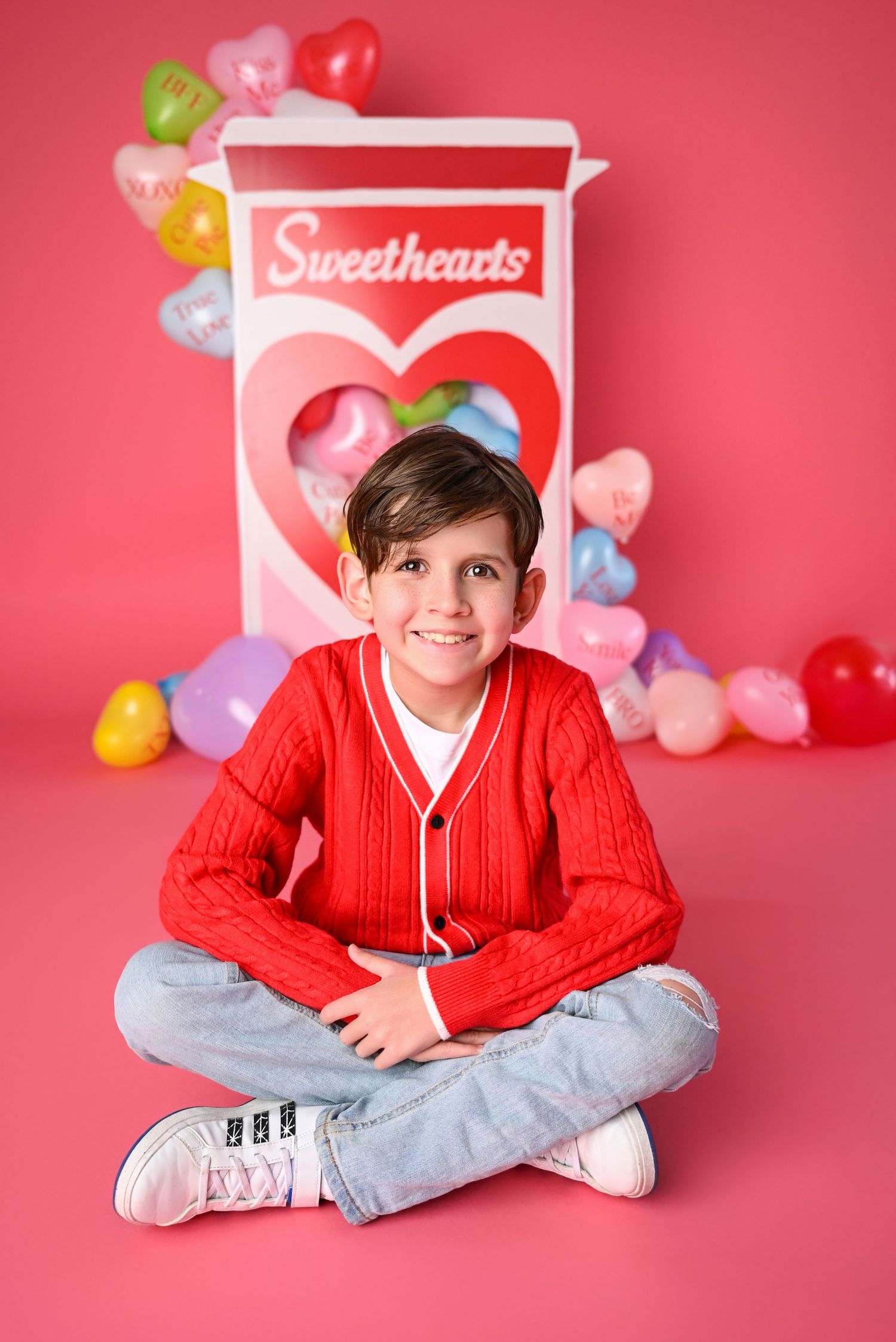Young boy smiling at the camera on hot pink background with Valentines Day Sweetheart candy backdrop. Arizona Mini session Holidays