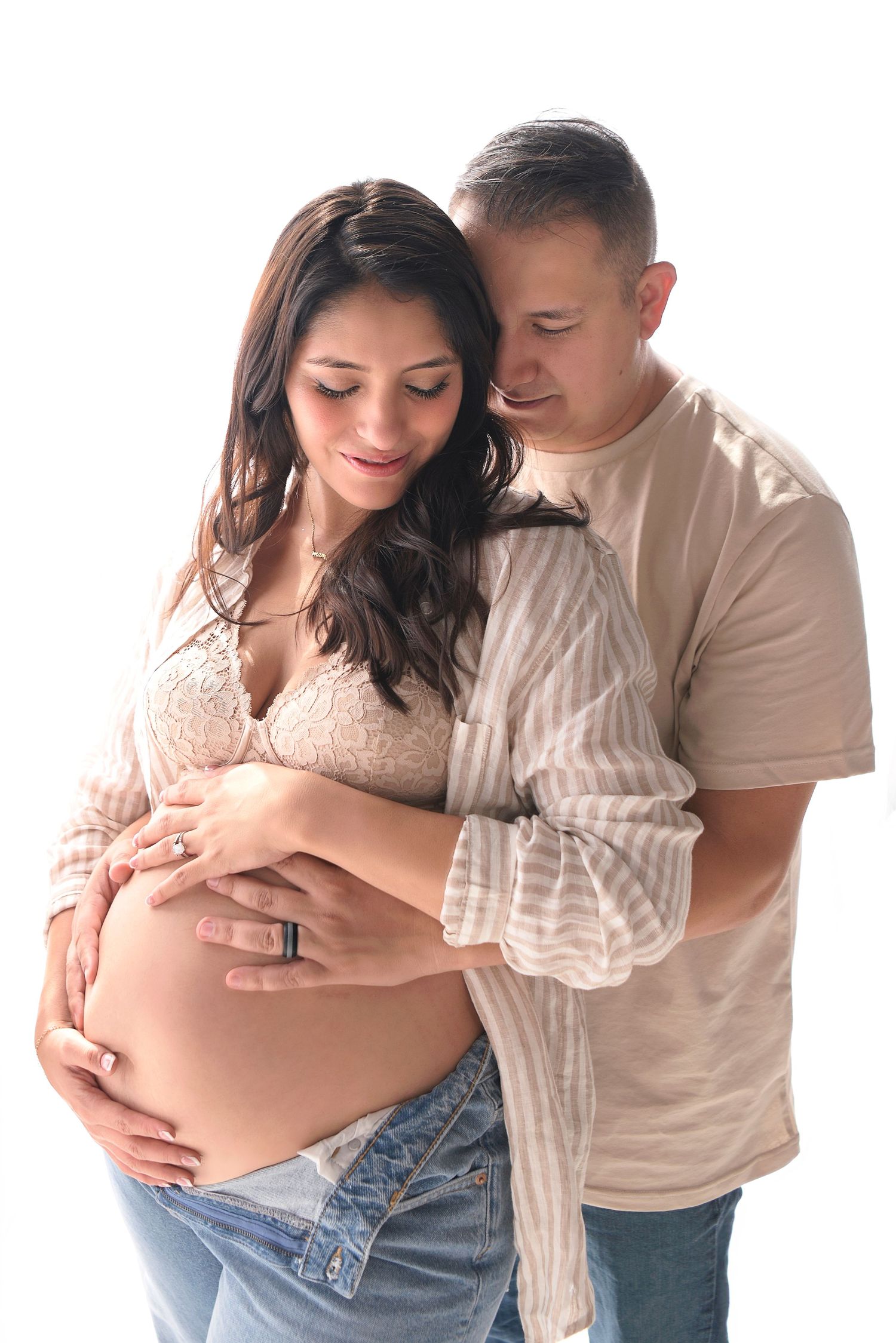 Couple cradles pregnant belly in backlit natural boho maternity image in Mesa, Arizona