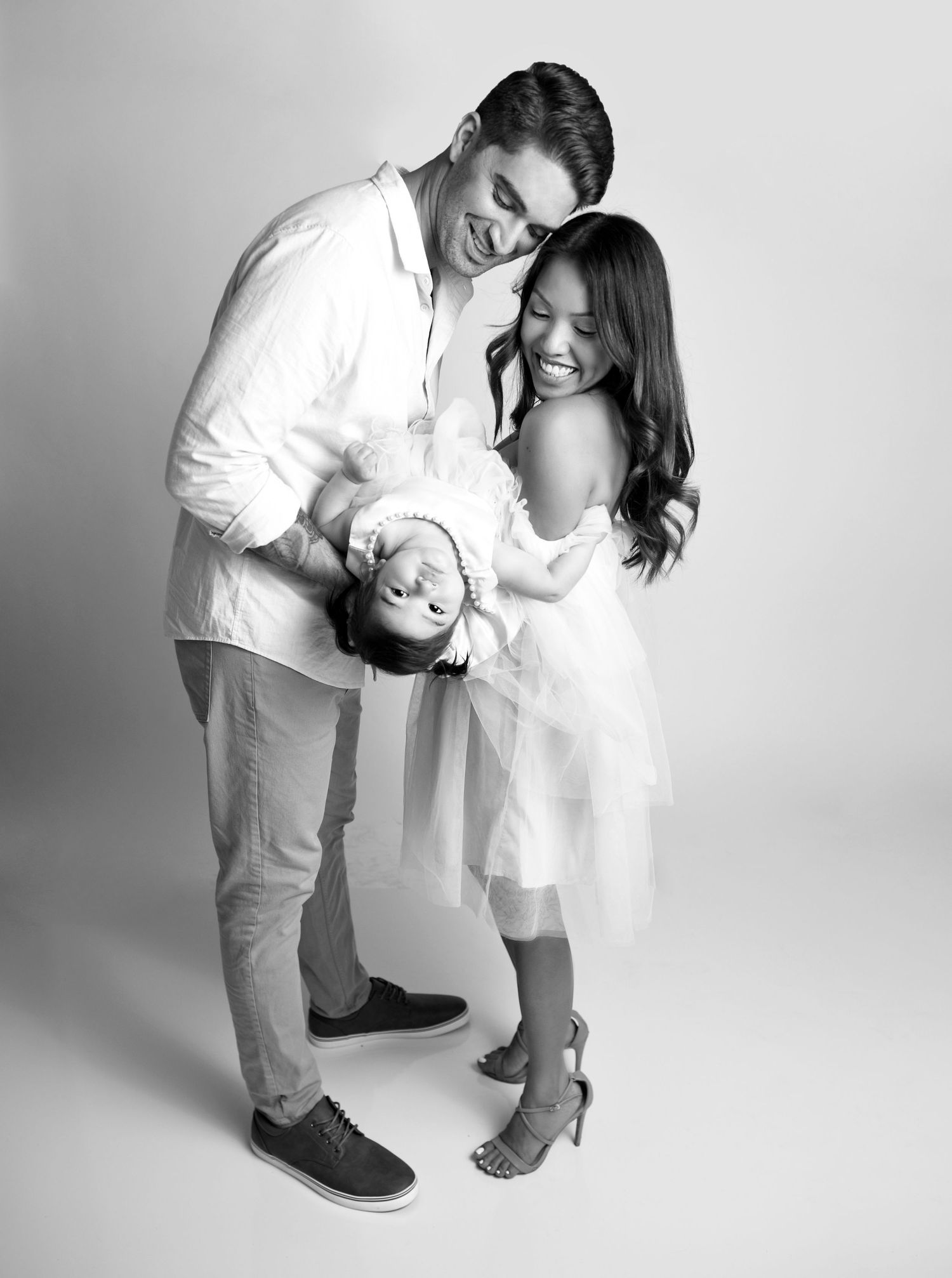 Family standing close together in a bright studio portrait.