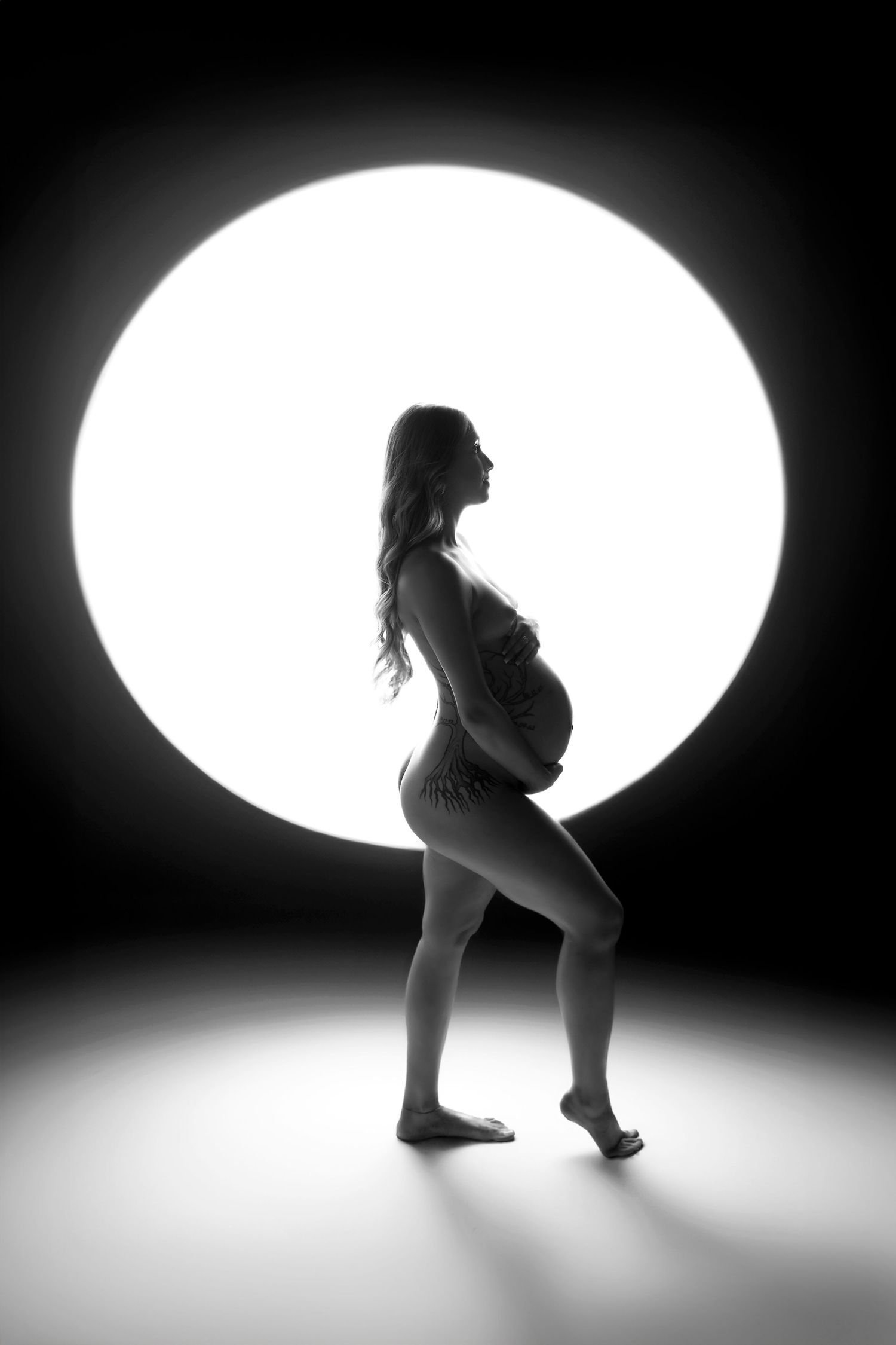Artistic black-and-white boudoir maternity shot focusing on form and silhouette.