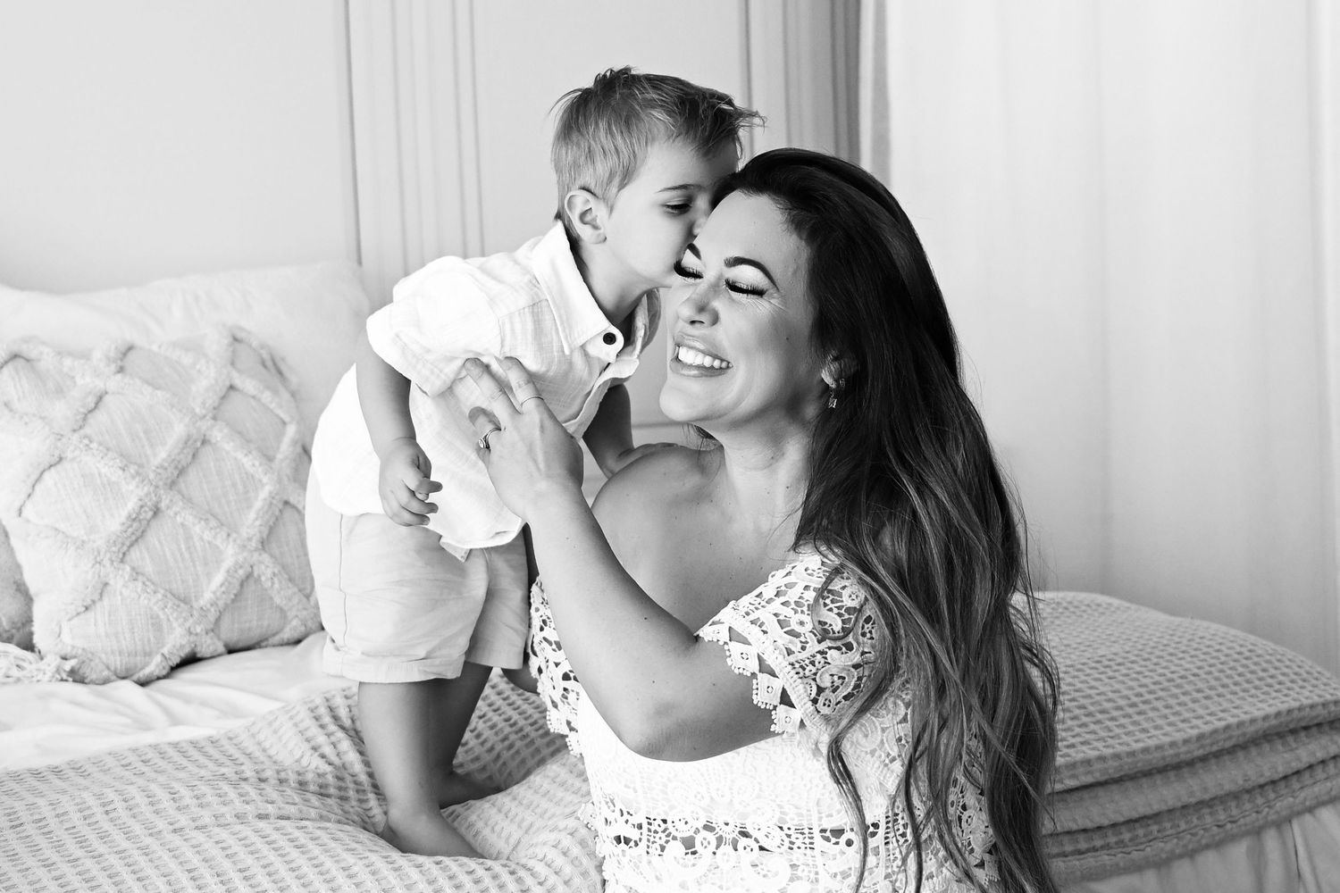 Toddler gives his Mama a kiss on the cheek in black and white candid homey photo