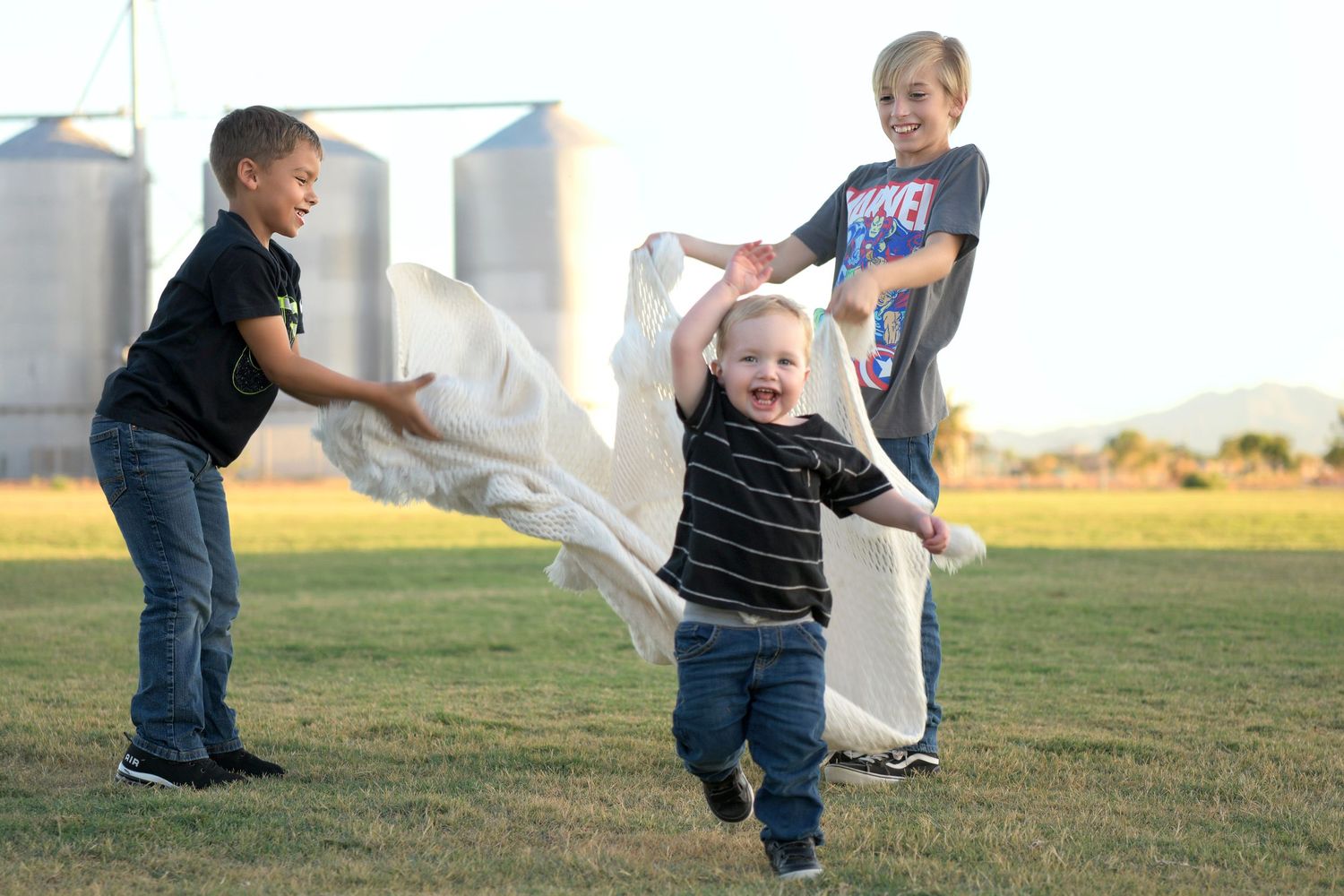 Children playing tag in an open field with mountain views.