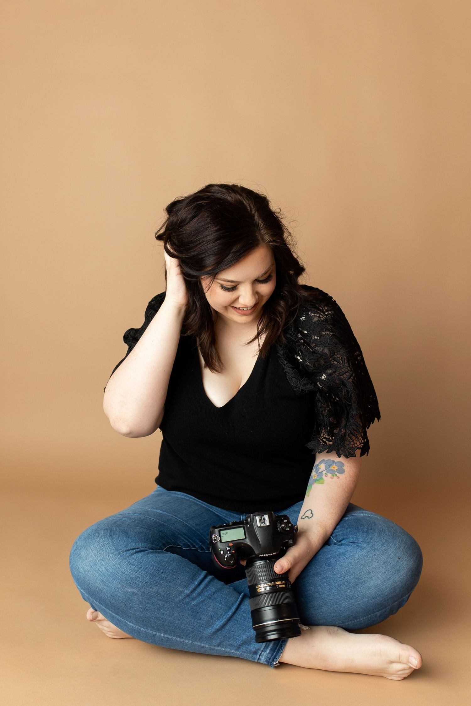Olivia Grace Selin of Olivia Grace Photography in Arizona looking at her camera in a photography studio headshot.