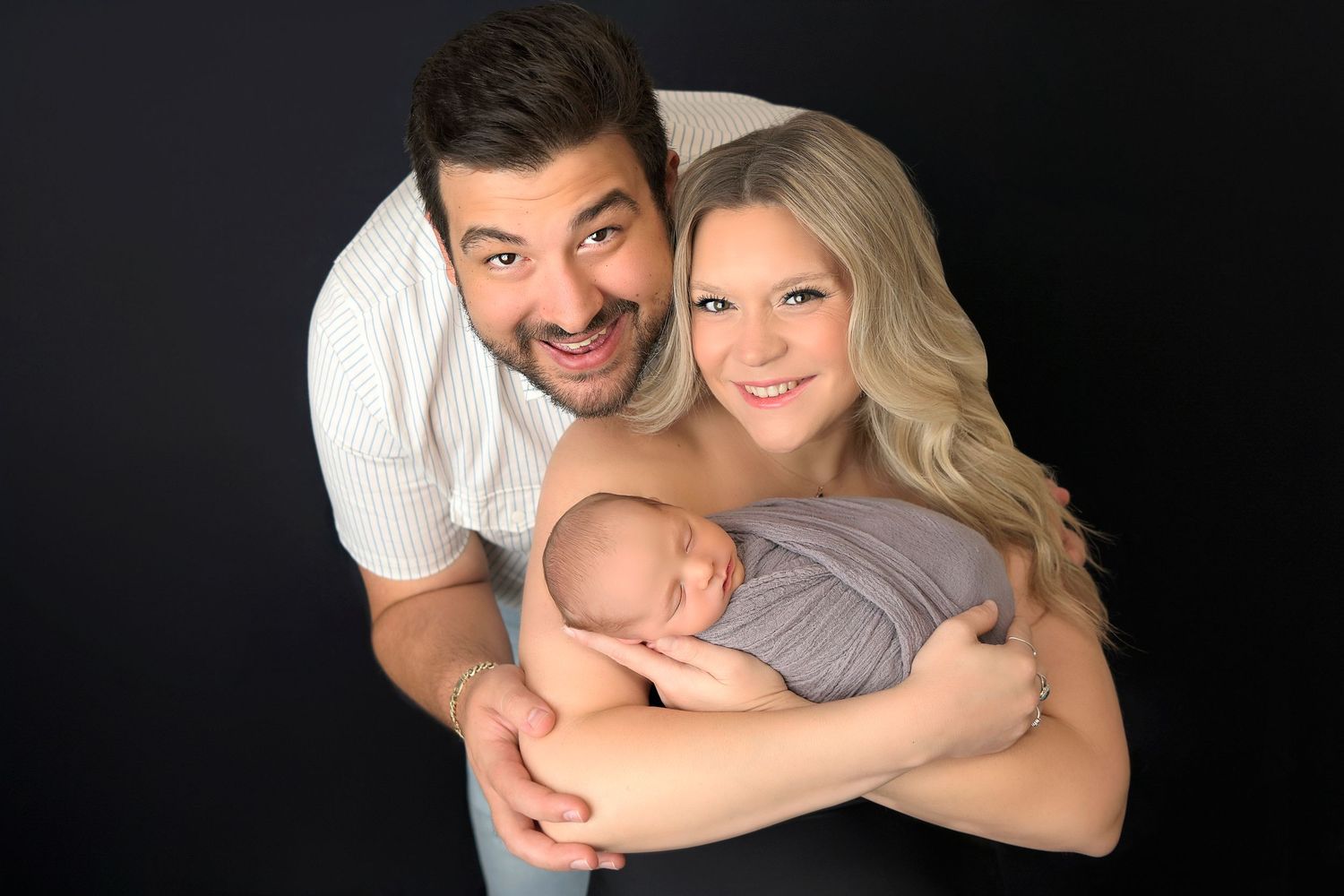 New parents cradle newborn baby son in grey swaddle in Ahwatukee Arizona