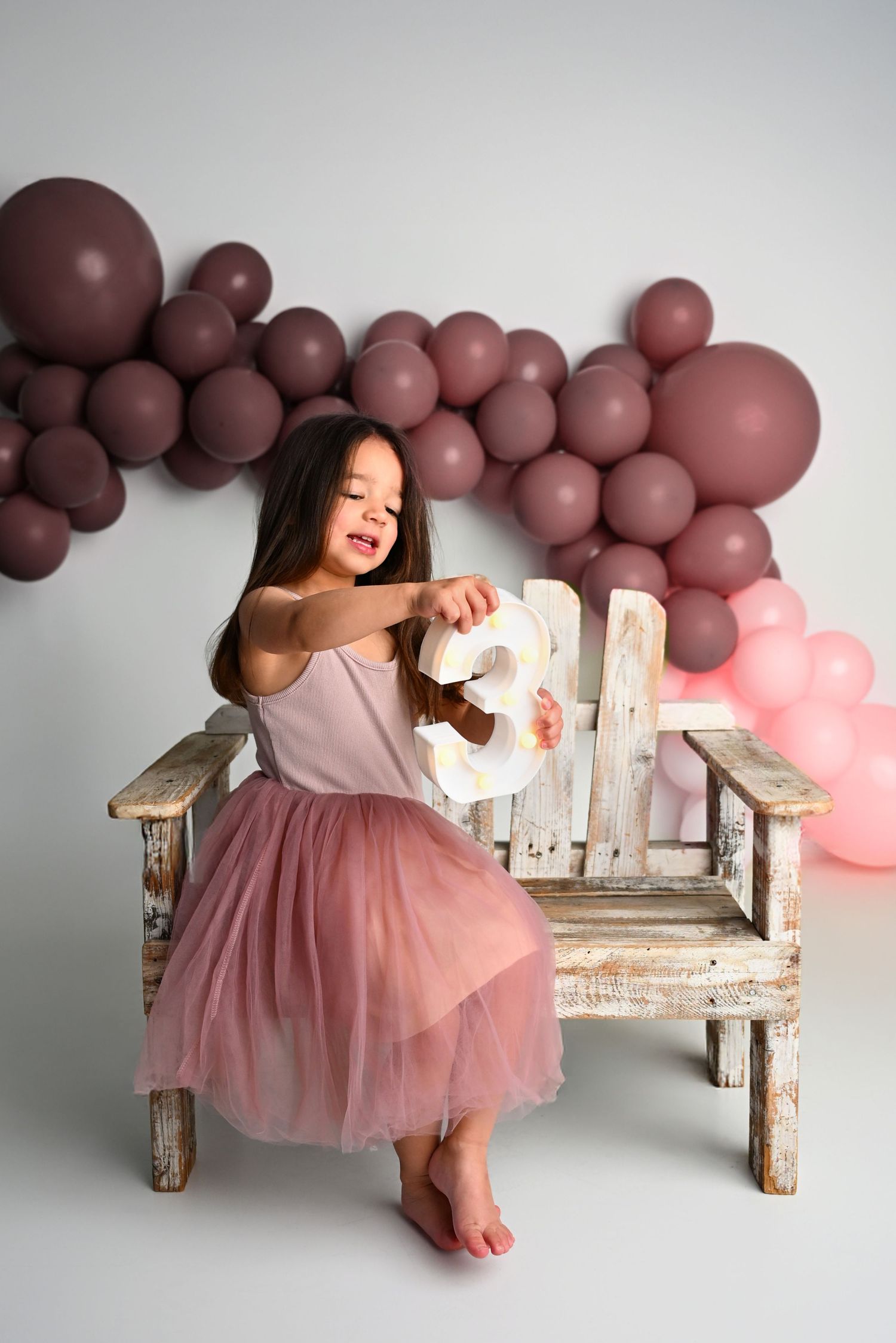 Three year pink and purple balloon arch garland photoshoot with a 3 smiling baby girl Paradise Valley Scottsdale Arizona