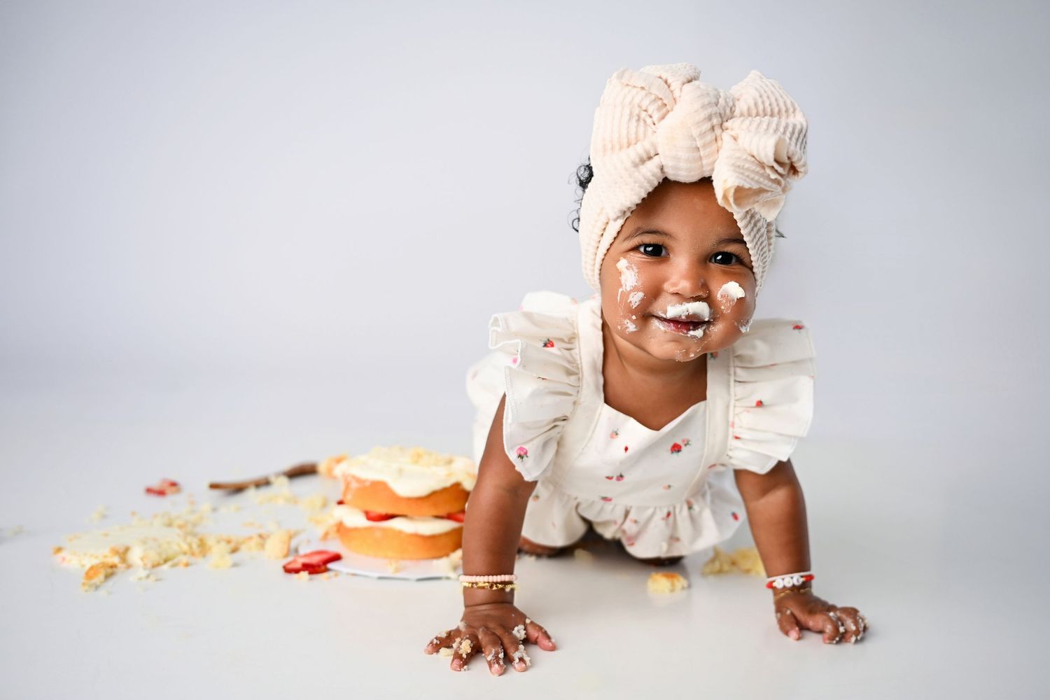 One year old baby covered in frosting from white smash cake session in Phoenix Studio