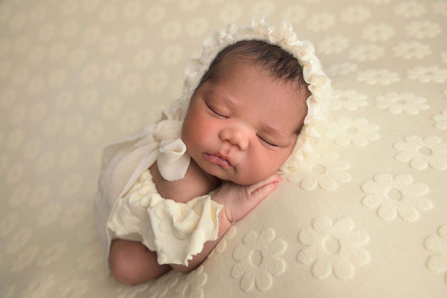 Baby girl in a bonnet with cream monotone set sleeps peacefully for her newborn session with Olivia Grace Photography