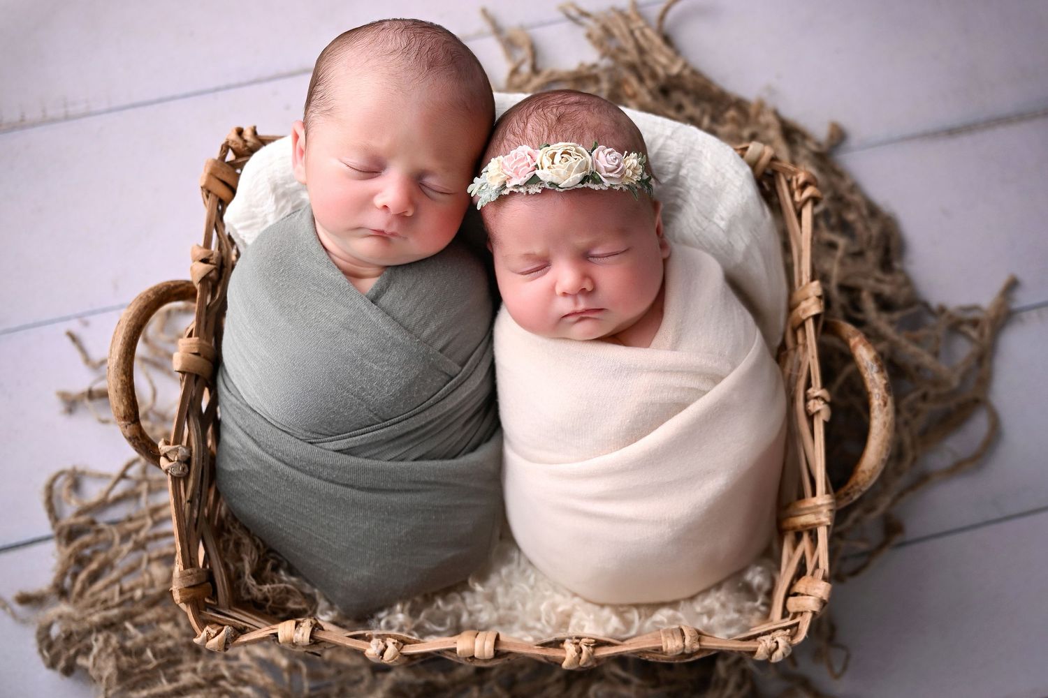 Newborn boy and girl twins swaddled in a basket