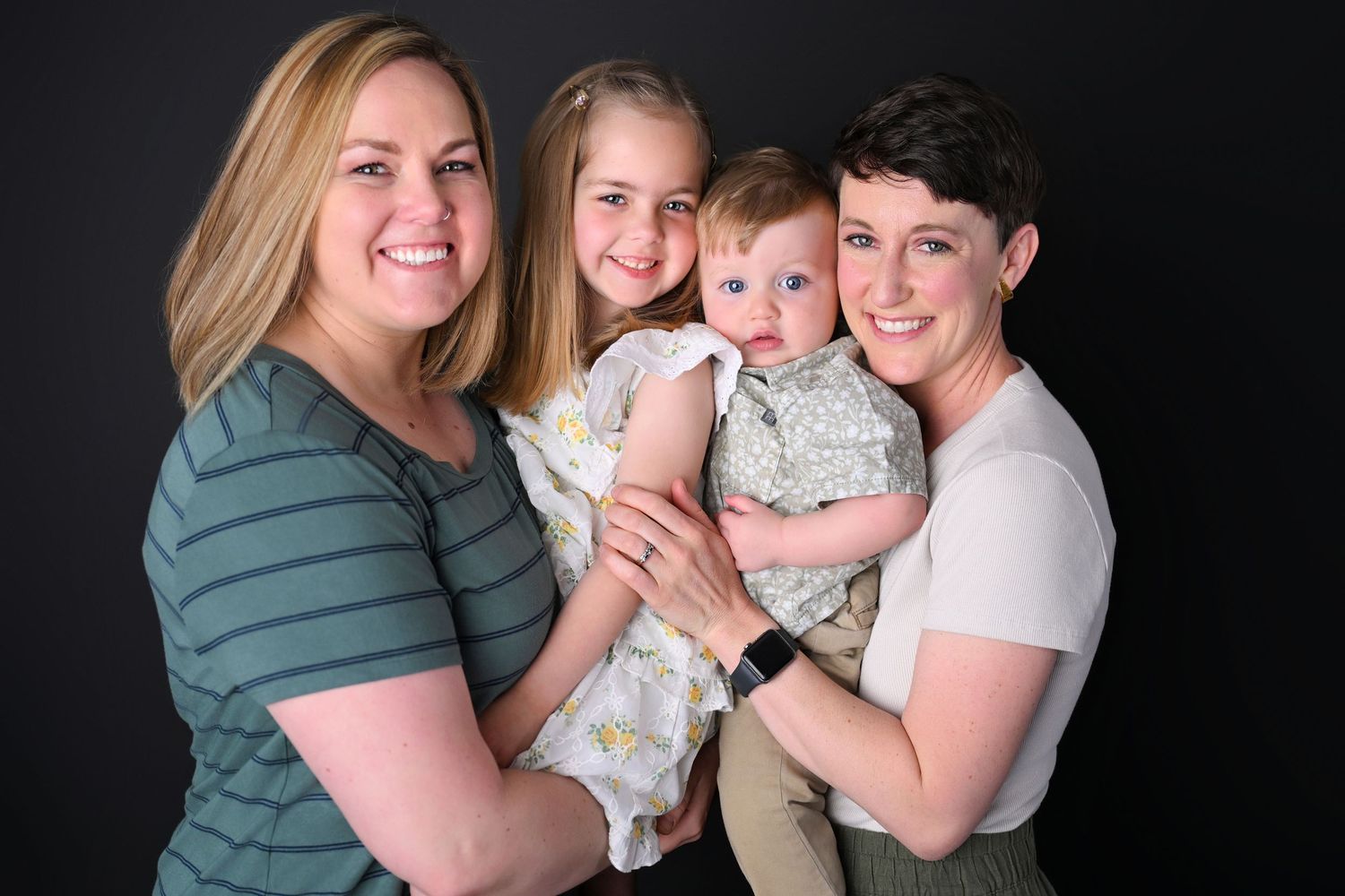 Lesbian Mother's standing snuggling their young toddlers close together
