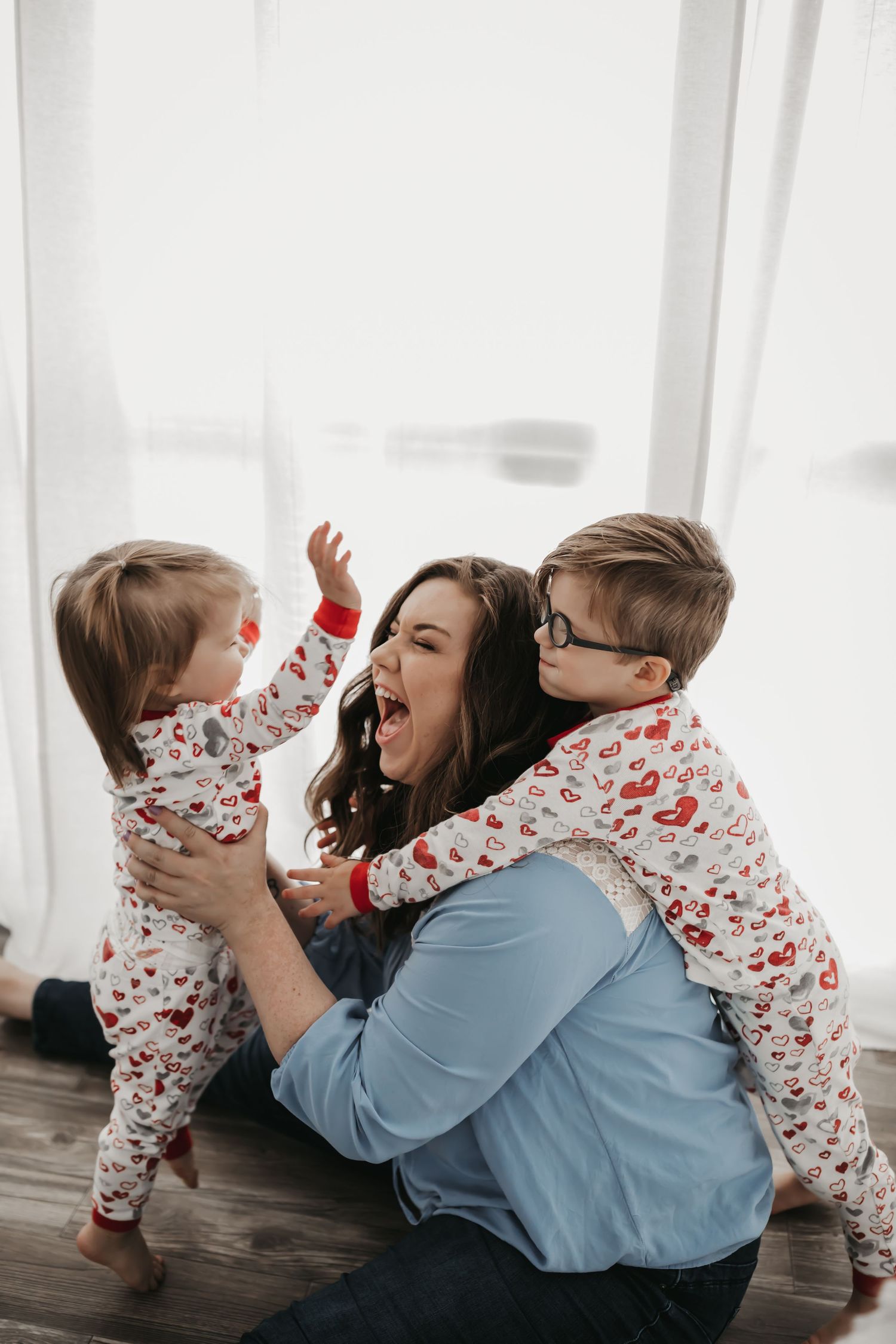 mother laughing with children in front of white curtains in lifestyle images