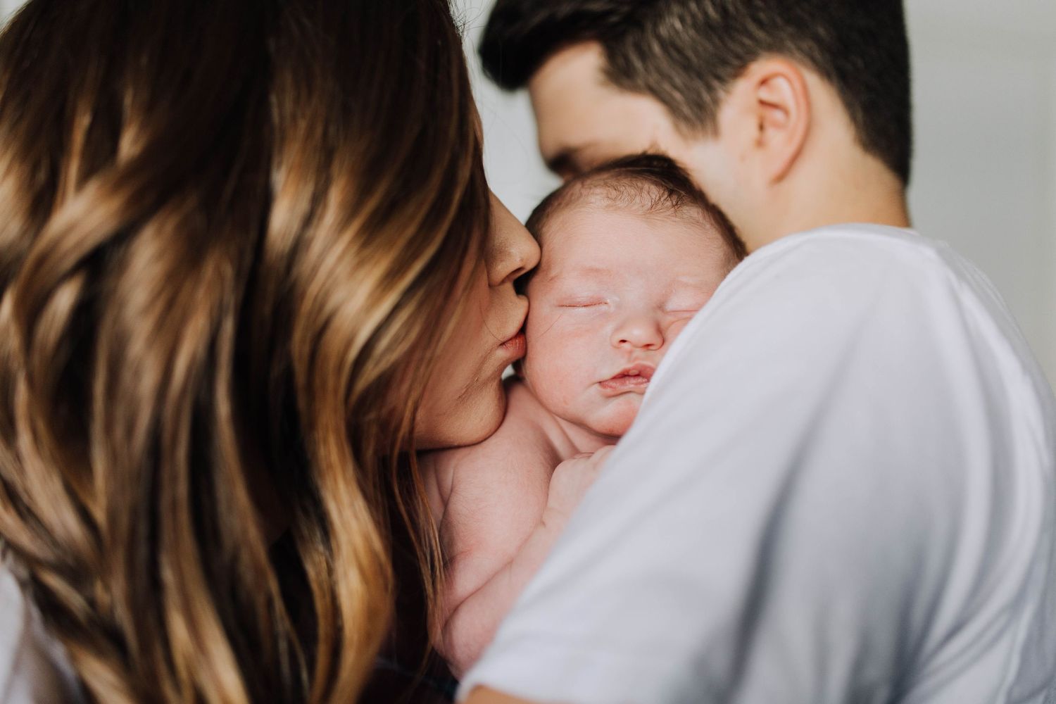 Lifestyle Newborn photo of mother kissing newborn baby boy