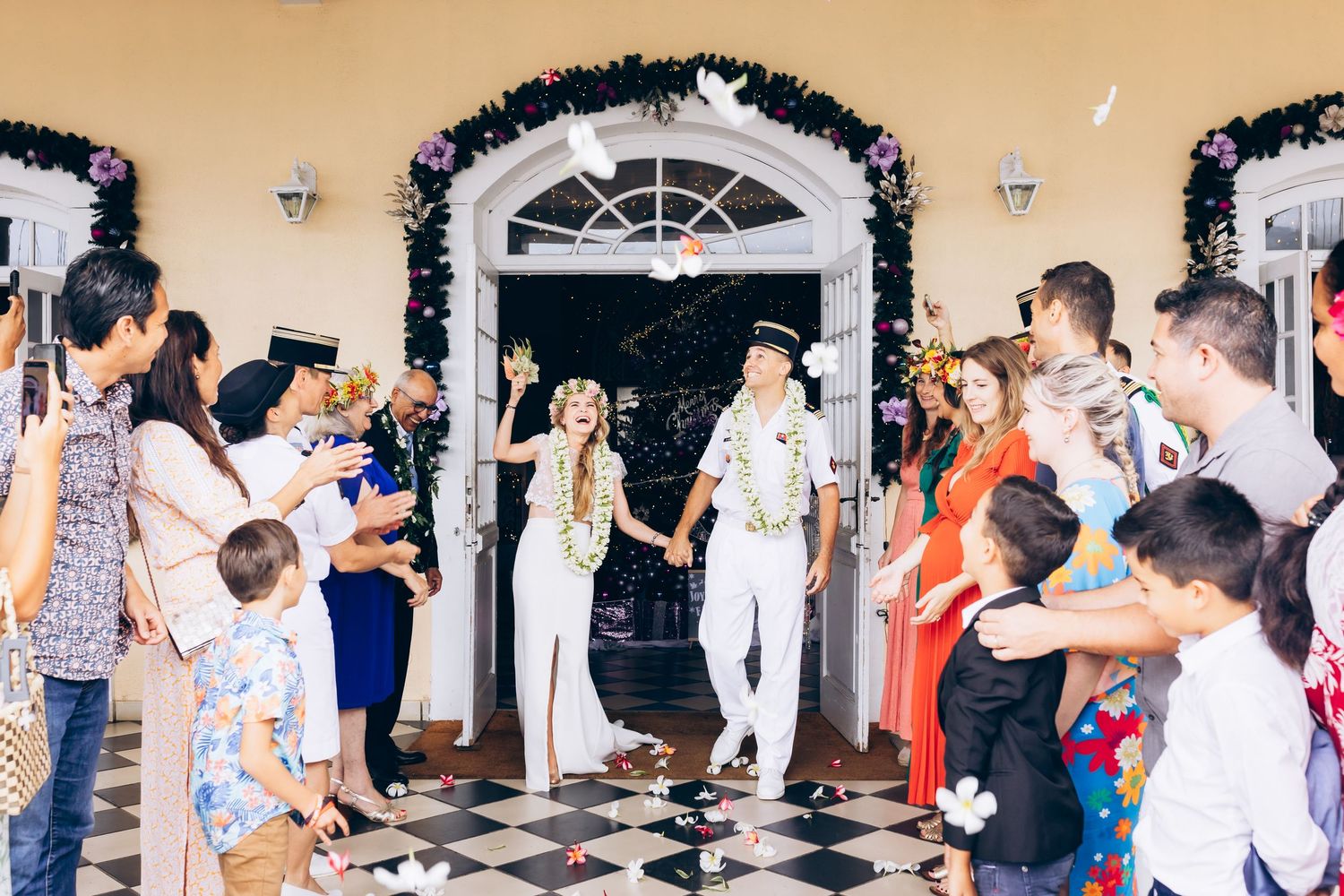Les jeunes mariés sortent d'un lieu de cérémonie décoré alors que les invités célèbrent avec des colombes blanches et des confettis.