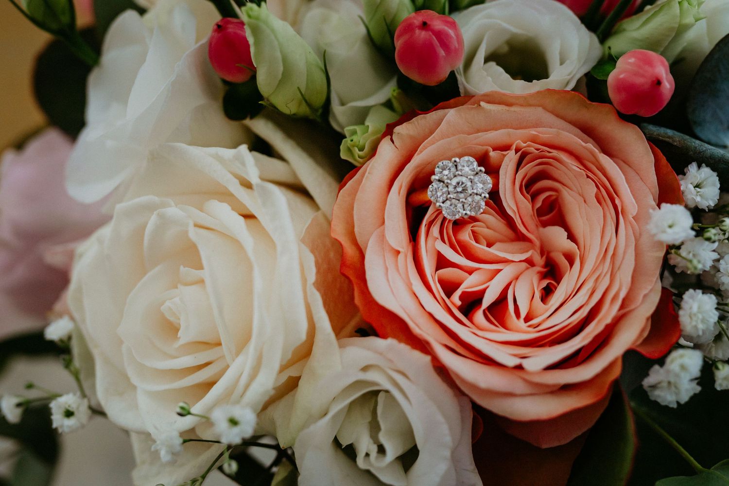 Gros plan d'une bague en diamant nichée dans un bouquet de mariée