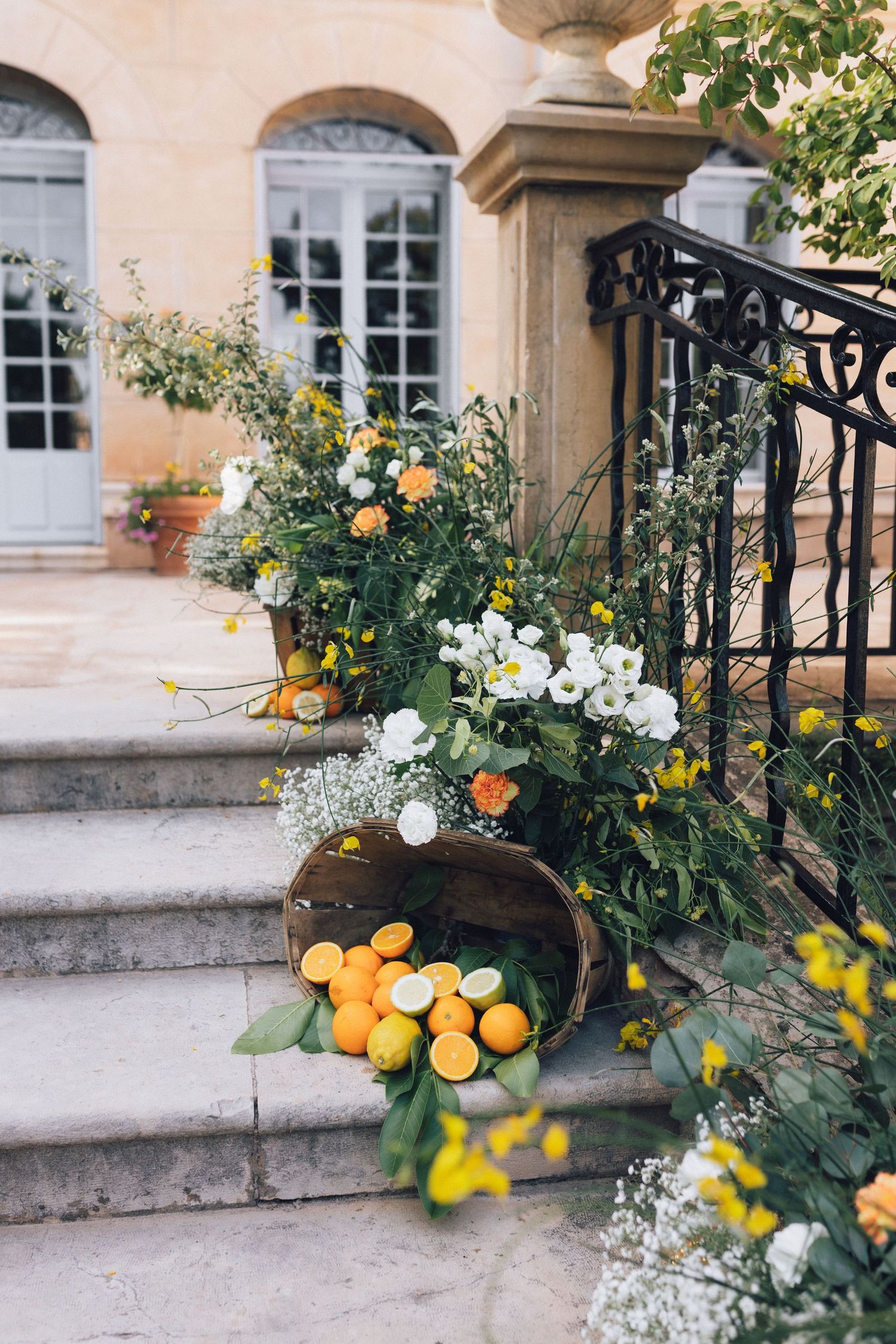 D'élégantes marches en pierre ornées d'agrumes, de fleurs blanches et jaunes et d'une végétation luxuriante à l'extérieur d'un château