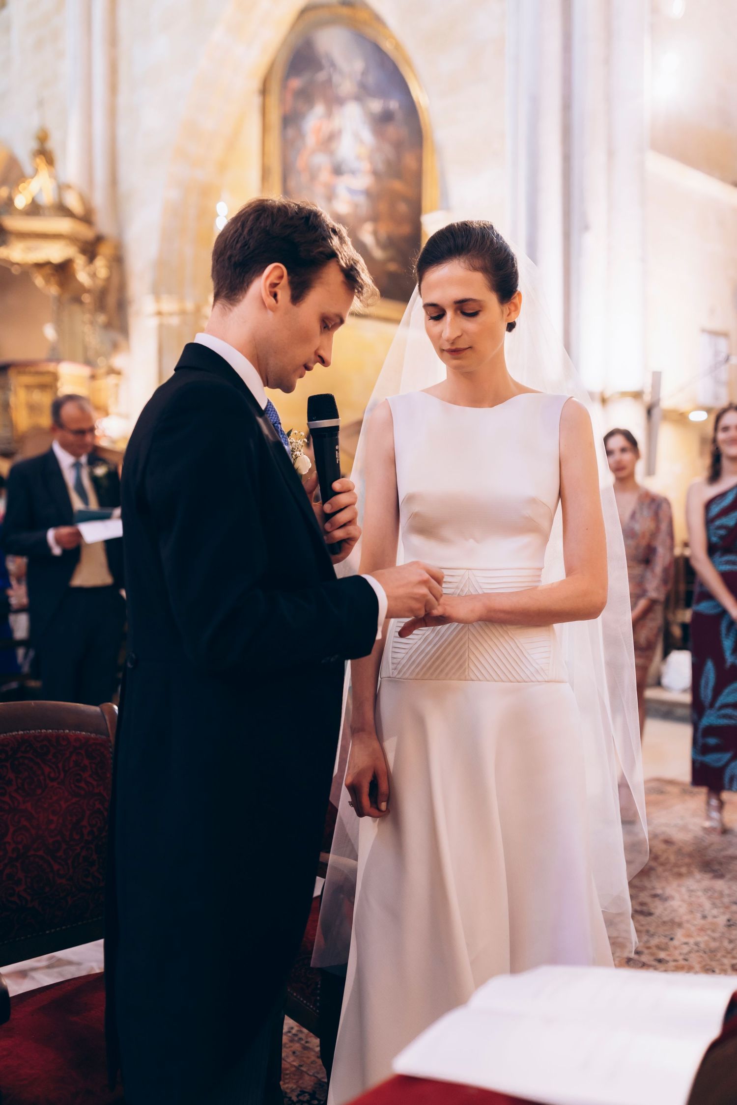 Marié passant l'alliance au doigt de la mariée lors d'une élégante cérémonie catholique, élégance et chic à la française