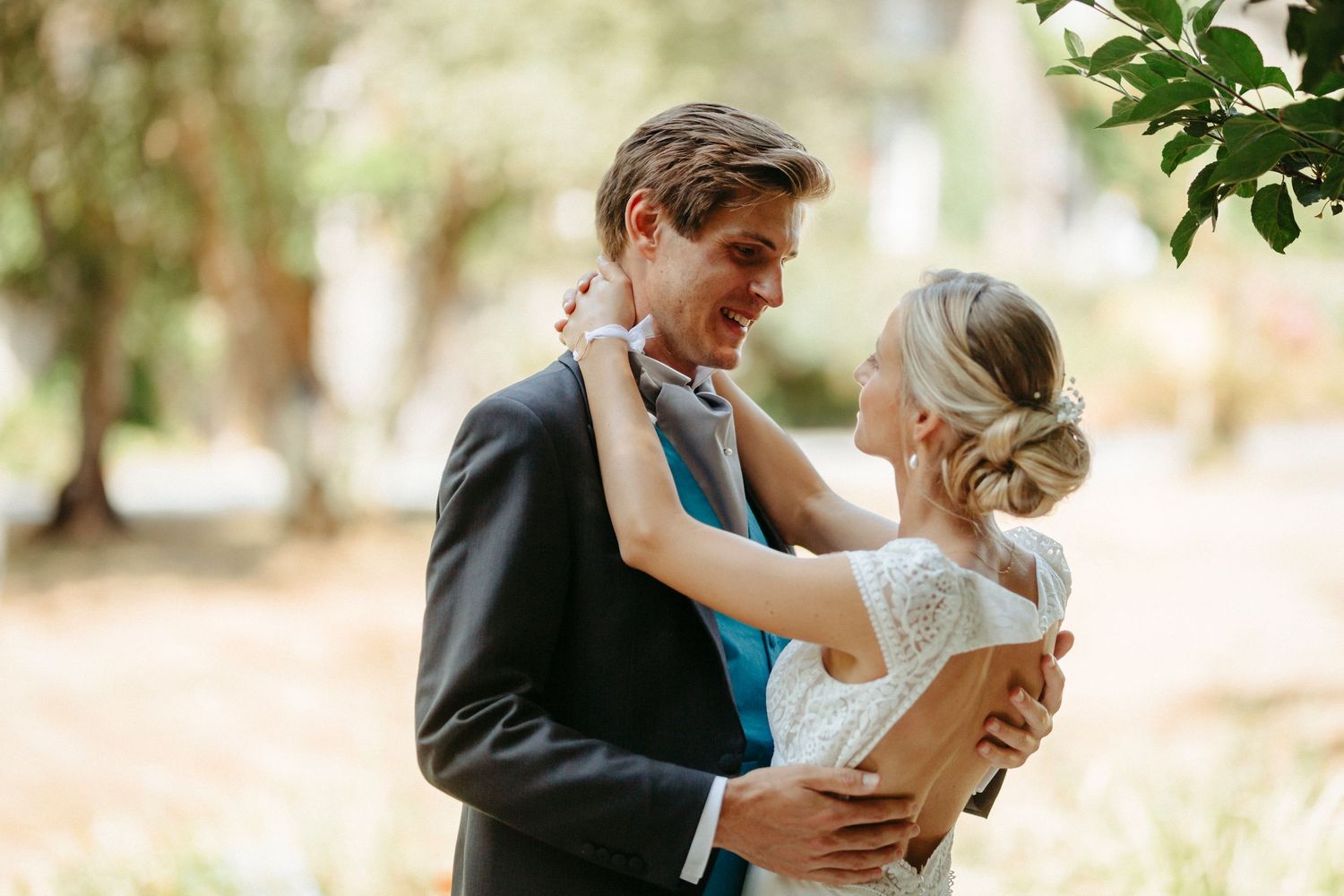 Une mariée et un marié partagent une étreinte romantique à l'extérieur, entourés d'arbres verts luxuriants le jour de leur mariage.