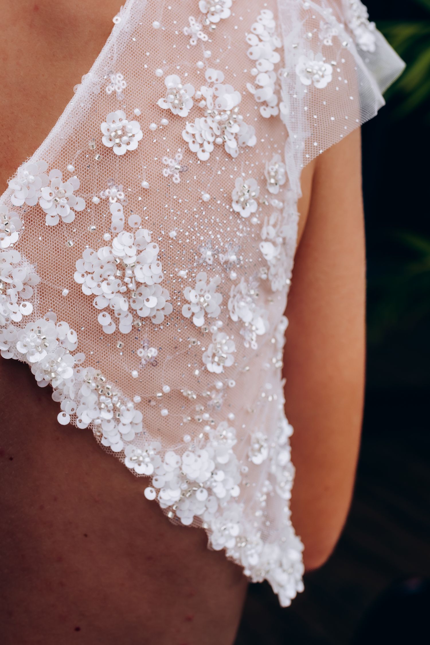 Détail en gros plan d'une broderie florale en dentelle perlée complexe sur une robe de mariée.