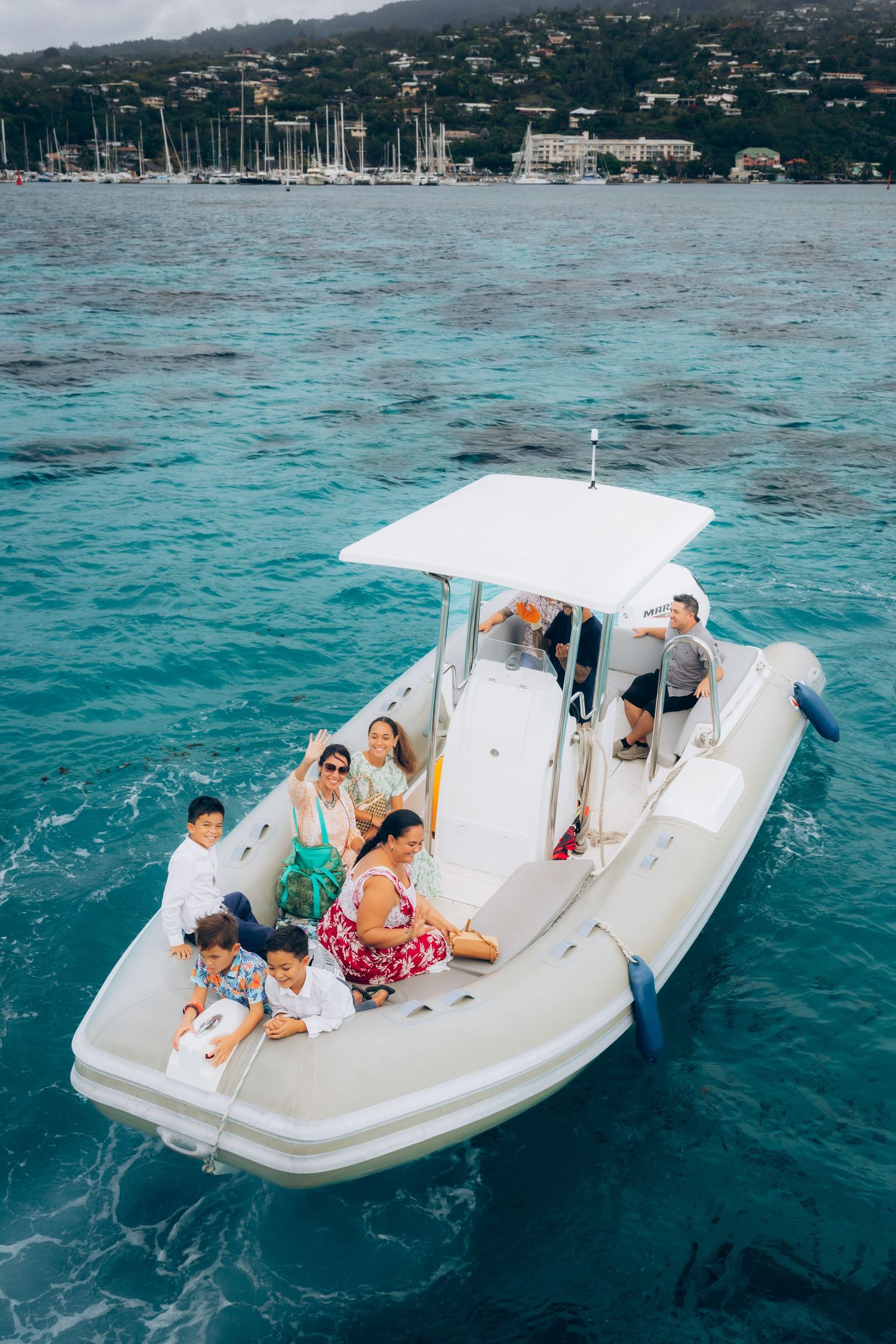 Groupe d'invités de mariage sur un bateau à moteur blanc au-dessus des eaux tropicales turquoises vibrantes.