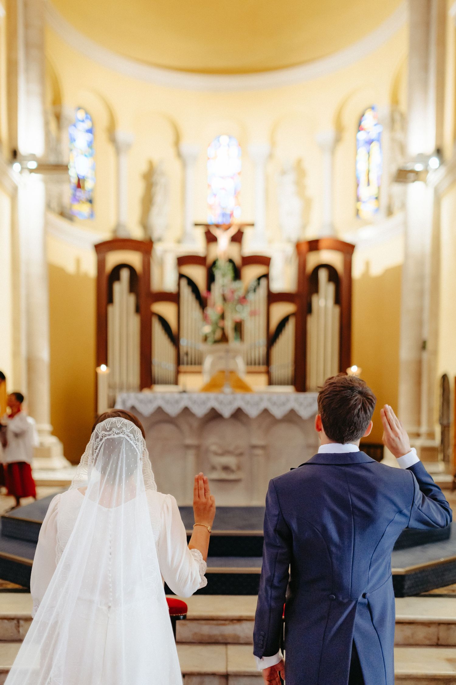 Une mariée et un marié lèvent la main en prière devant l'autel lors d'une cérémonie de mariage traditionnelle à l'église. Prière scoute